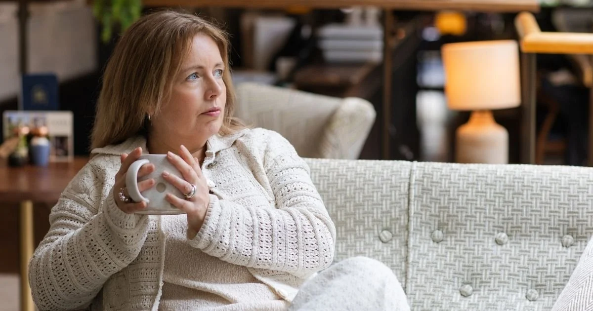 Sarah Robinson holding a mug and looking thoughtfully into the distance while reflecting on her experience of changing from Evorel Sequi to Evorel Conti HRT.