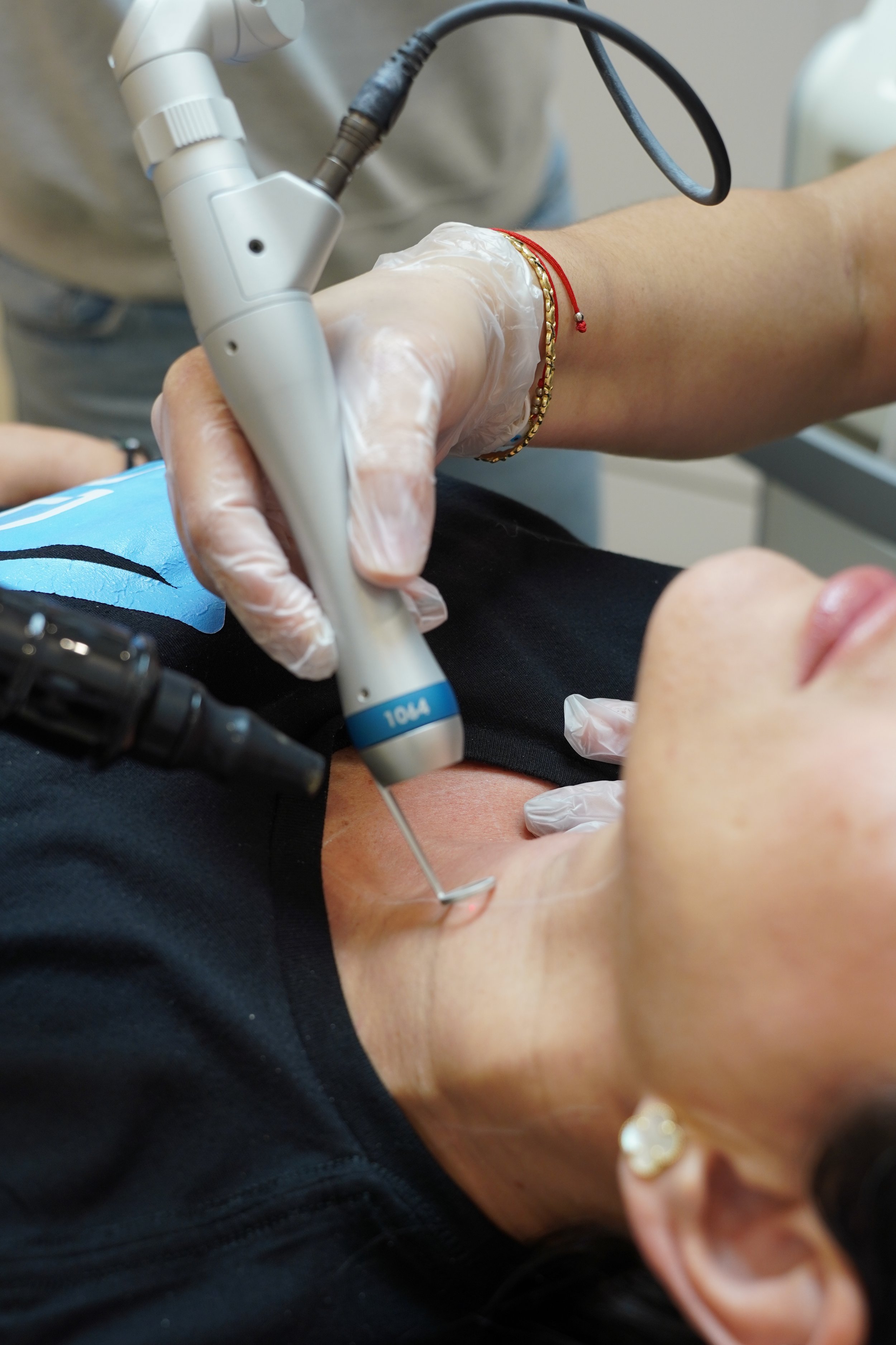 A person receiving a skin rejuvenation procedure on their neck with picoway laser, using a handheld device in a clinical setting.