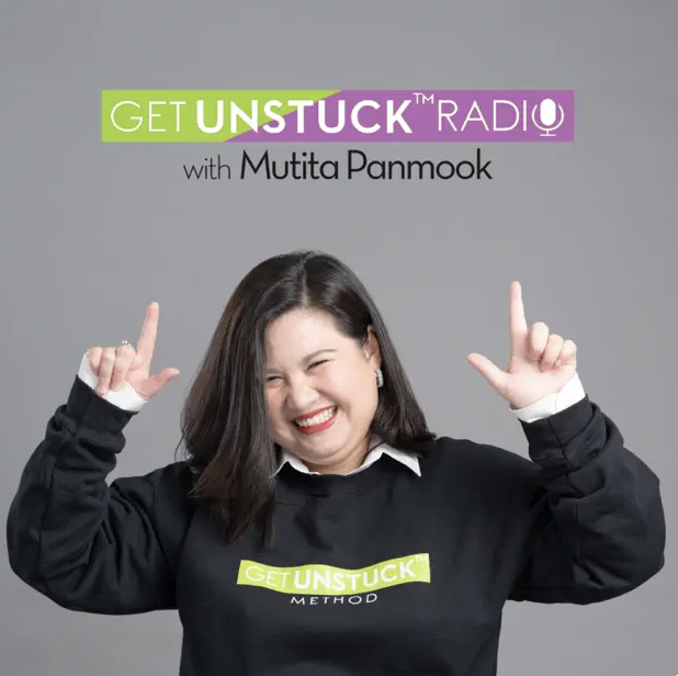Woman smiling and pointing upwards, wearing a black "Get Unstuck Method" sweatshirt. Grey background with text "Get Unstuck Radio with Mutita Panmook" at the top.