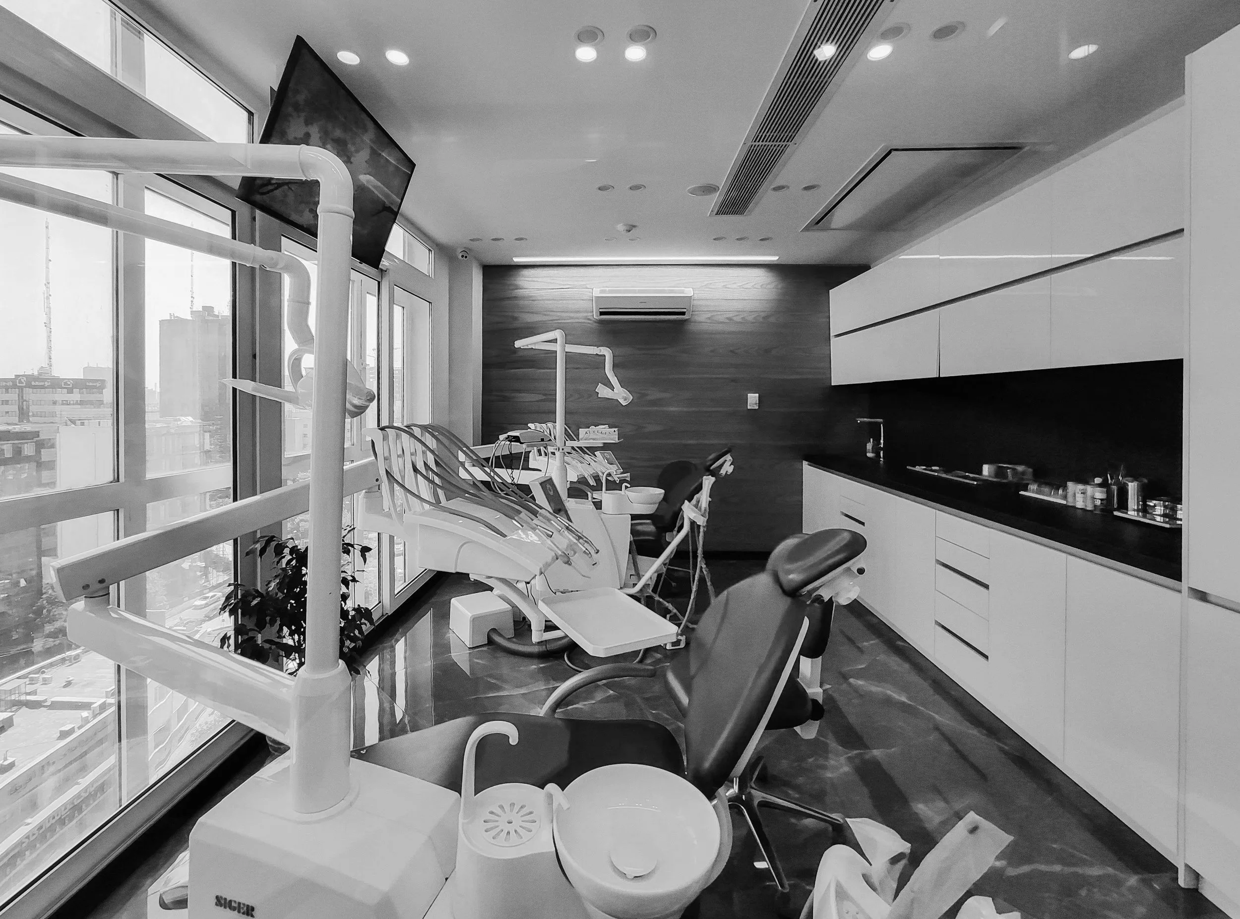 A modern dental clinic with dental chairs, equipment, and a large window showing city buildings.