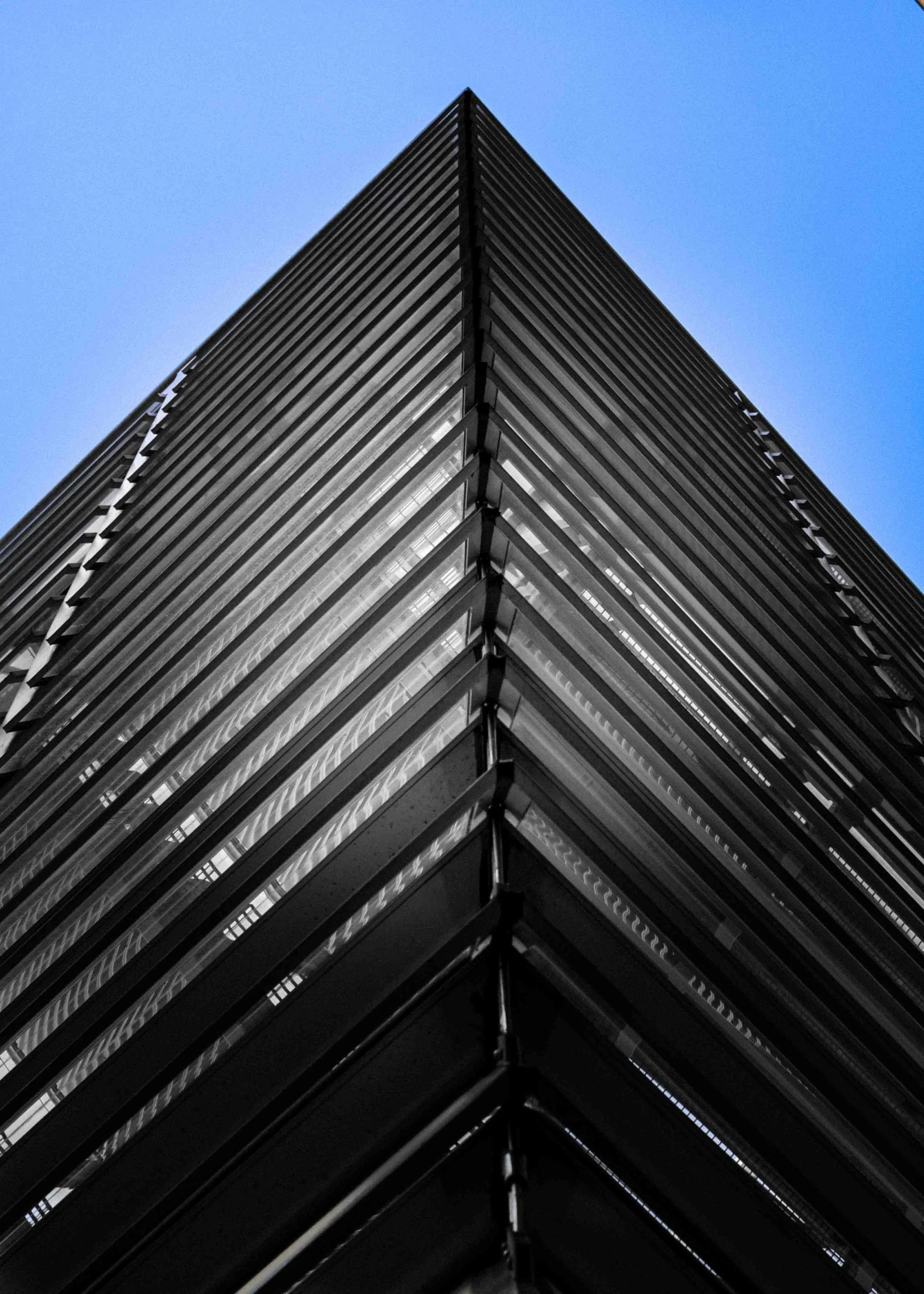 Low-angle view of a modern skyscraper with glass and metal exterior against a blue sky.