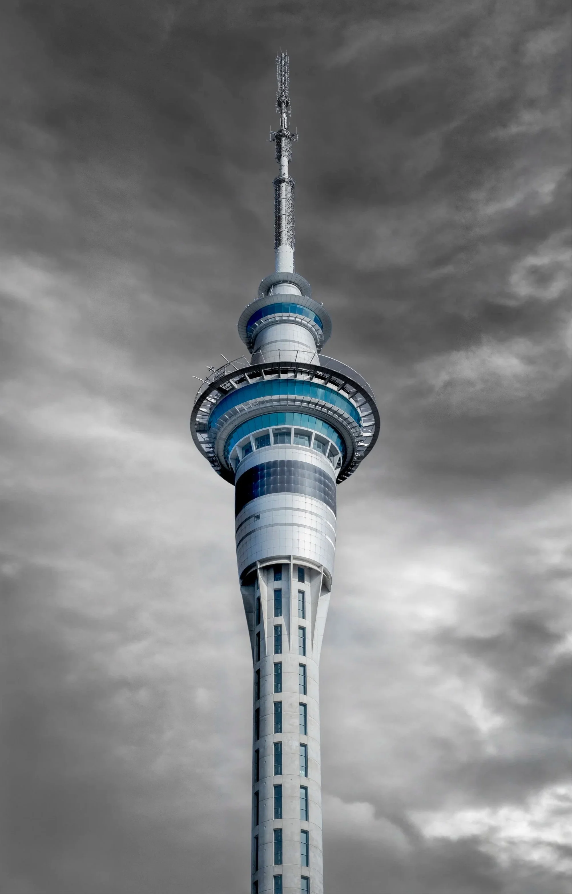 Sky Tower Auckland or tall communication tower with multiple antennas, set against a cloudy sky.