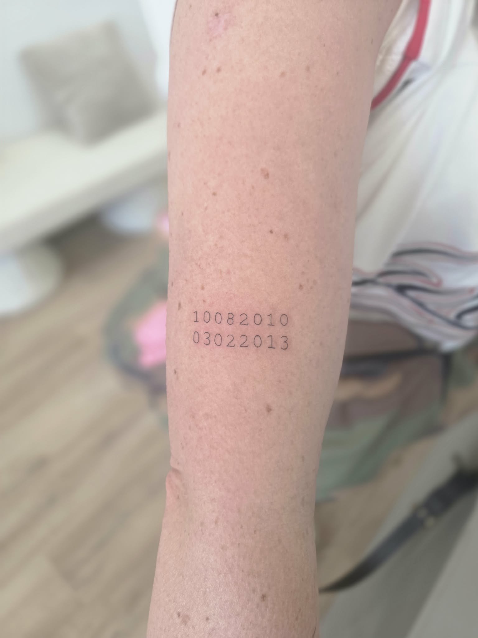 A close-up of a person's inner forearm with a clean fine line tattoo featuring two lines of numbers. Fine line rose tattoo by Heart and Home Tattoo, Moonee Ponds Melbourne