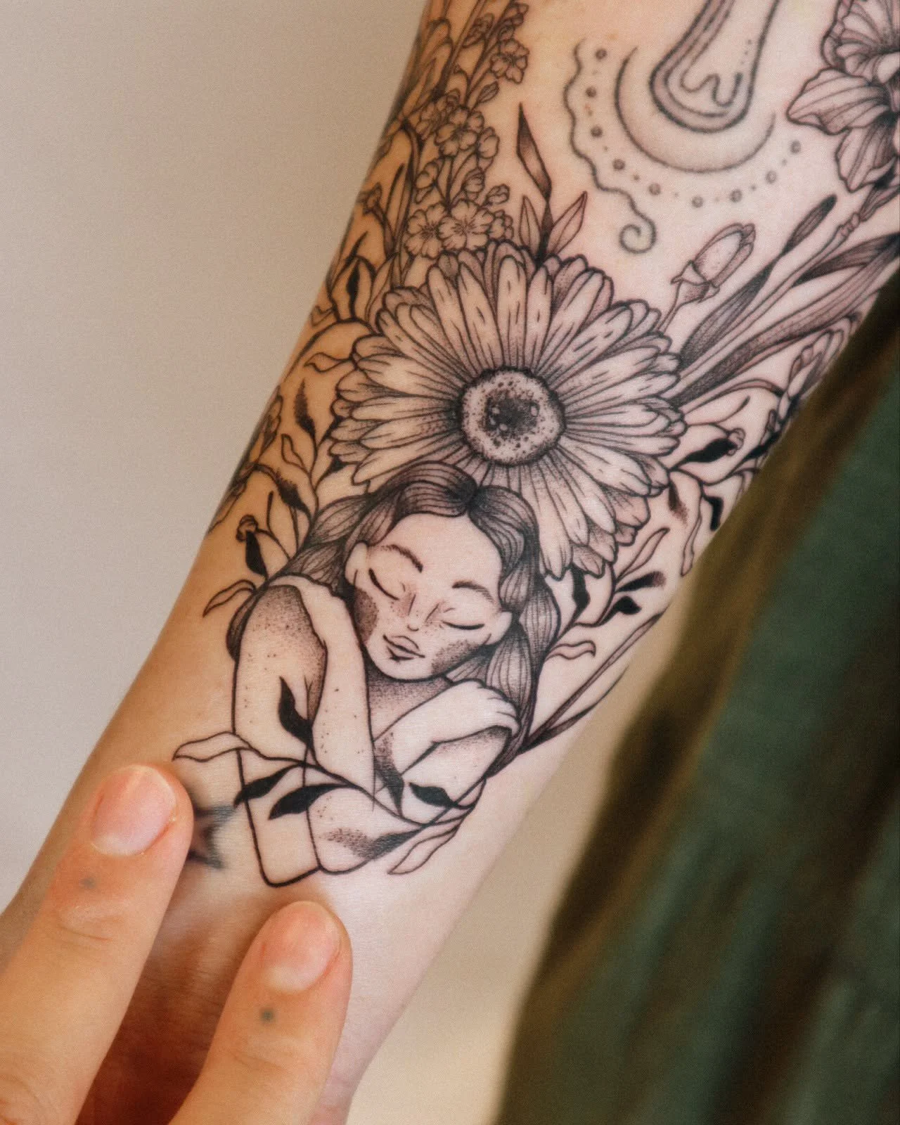Black and white tattoo of a sleeping girl with flowers and a large daisy above her head.