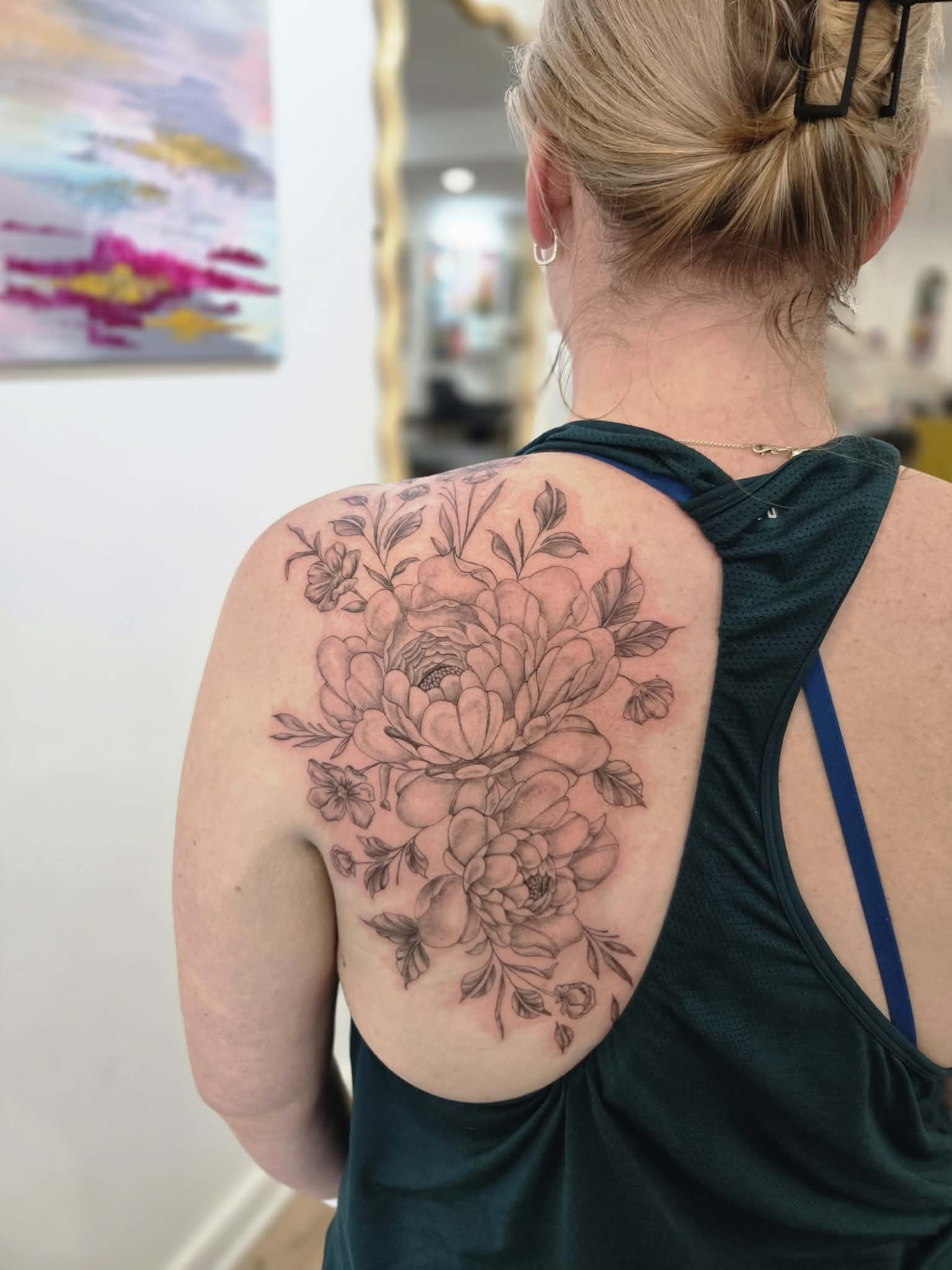 A woman with blonde hair styled in a bun, wearing a black tank top, shows a large floral tattoo on her shoulder and upper arm, with detailed line work of blooming flowers and leaves. fine-line-rose-tattoo-melbourne-moonee-ponds.jpg
minimalist-tattoo