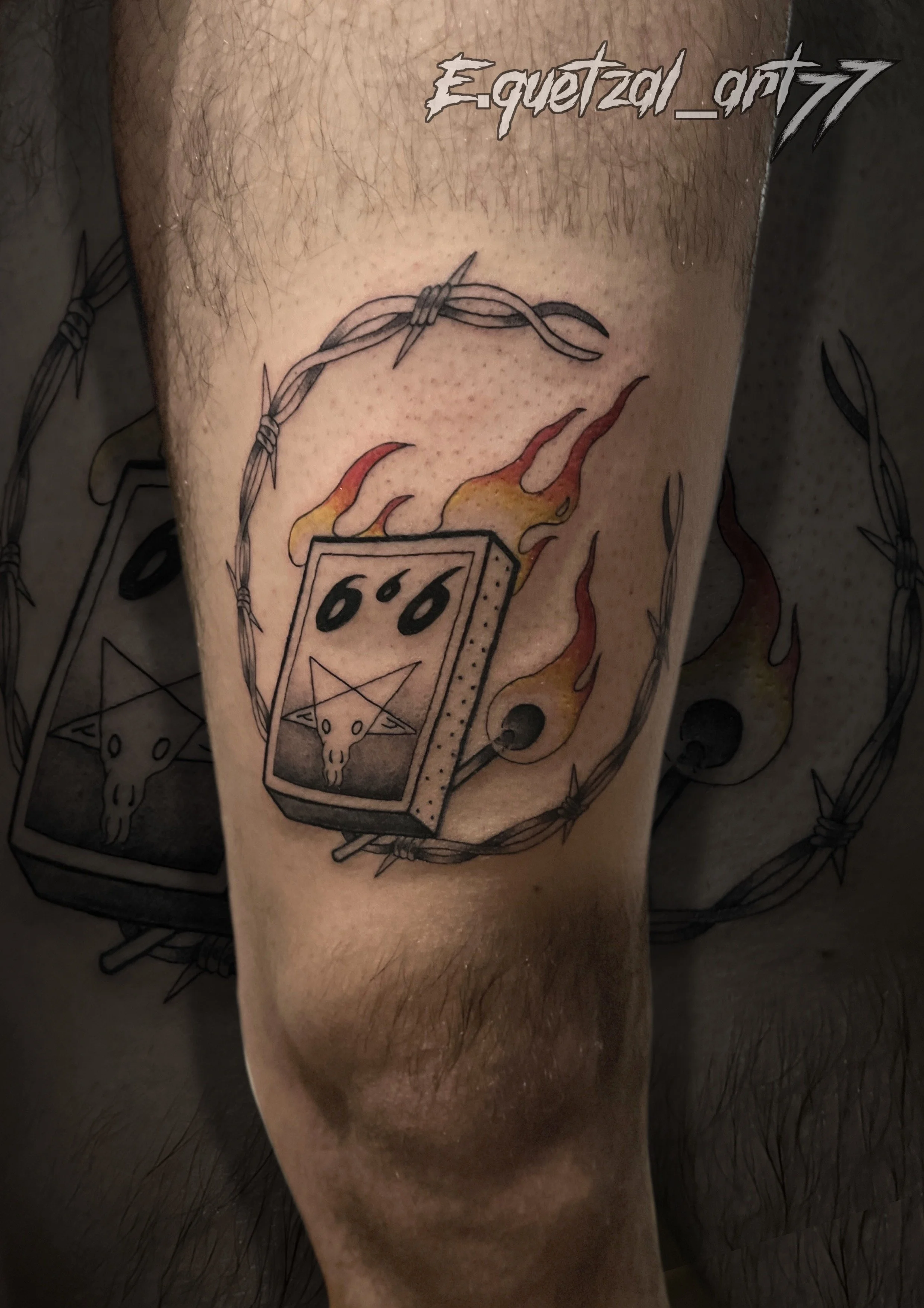 Tattoo of a burning deck of cards with a goat skull, surrounded by a barbed wire circle on a person's arm.