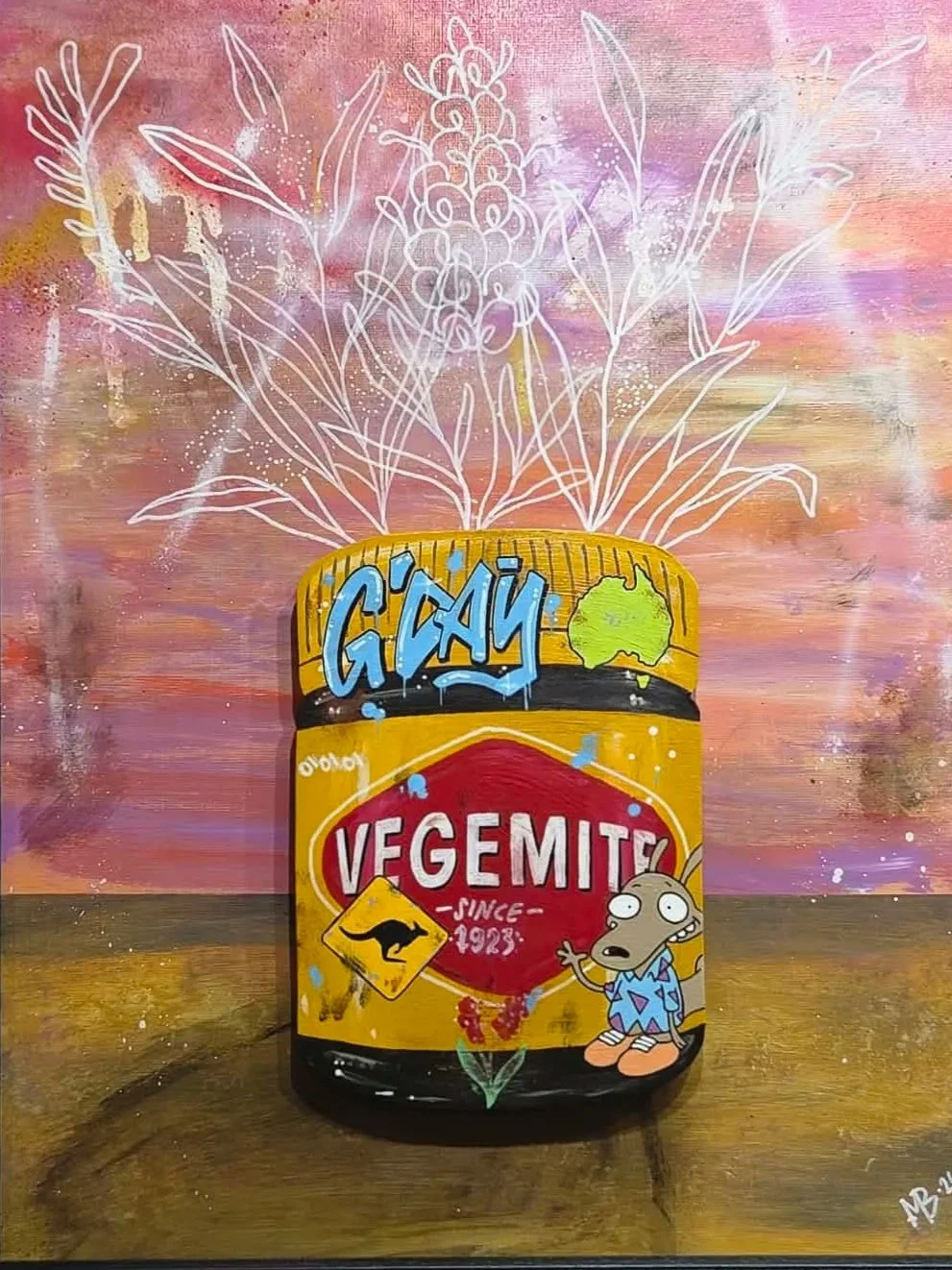 Street art of Vegemite jar with a cartoon character in pajamas, set against a colorful background with white line drawing of flowers behind.