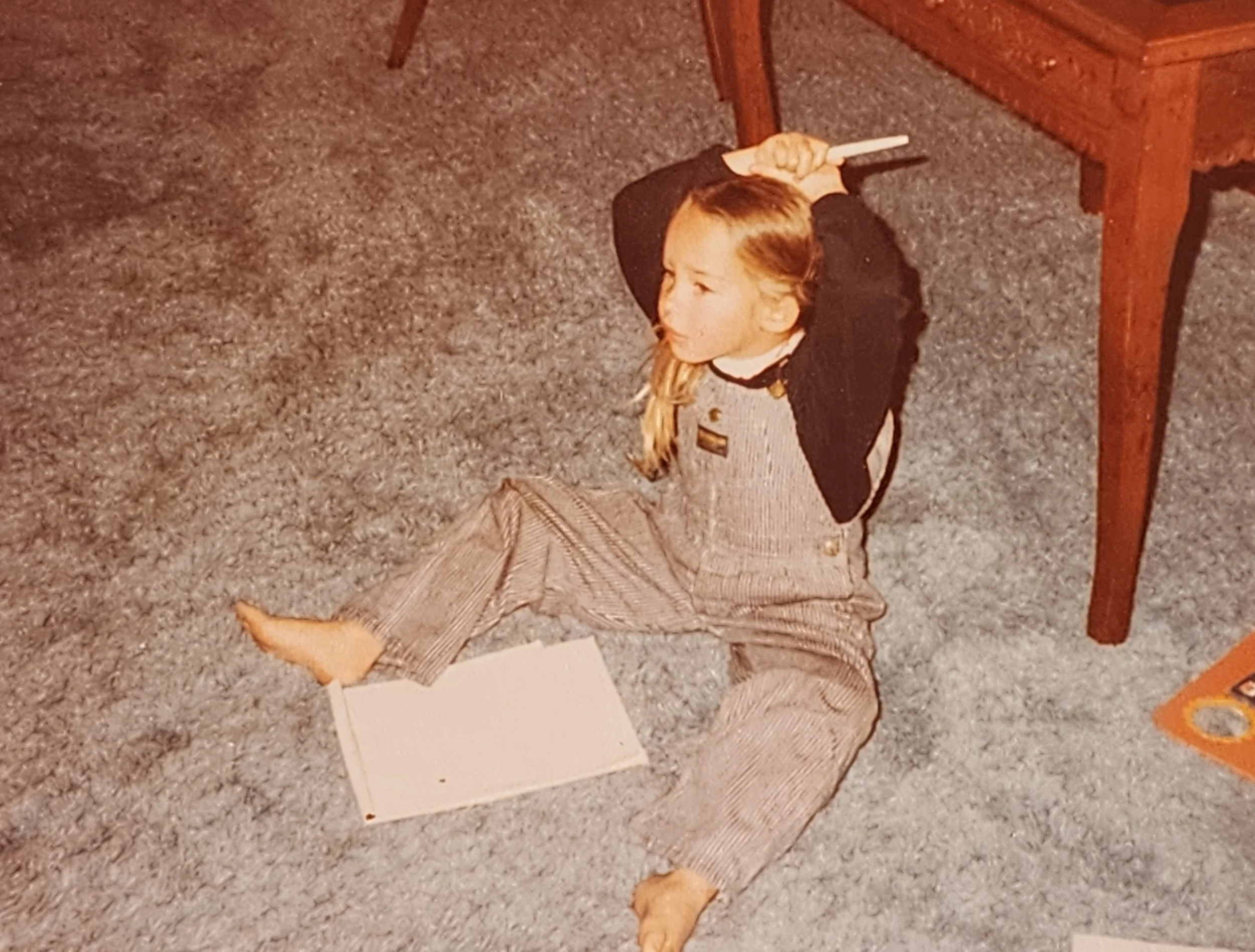 The artist as a child, preparing to draw or cast a spell with a pen over their head.