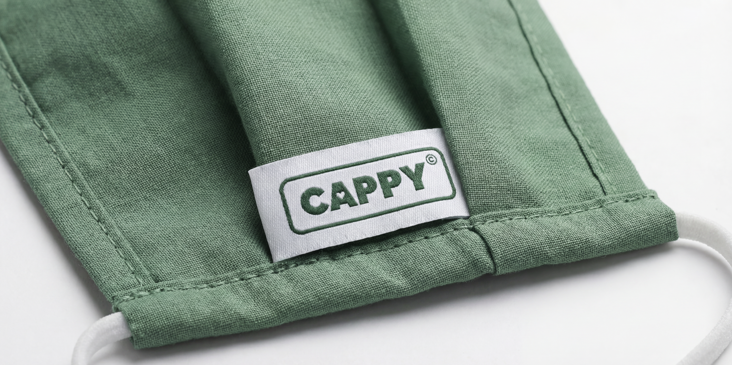 Close-up of a green fabric face mask with a white tag that reads 'CAPPY' in green letters.