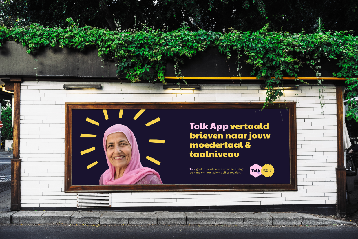 Billboard on a brick wall featuring a smiling woman in a pink headscarf with a halo-like yellow design around her head. The billboard promotes the Tolk App, which translates letters to the user's native language and level. The background is purple, and the text is in Dutch.