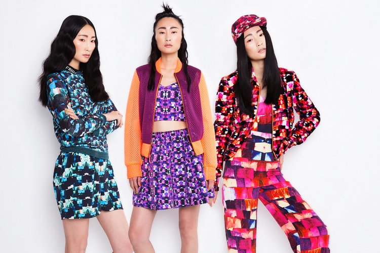 Three women in colorful, patterned clothing standing against a white background.