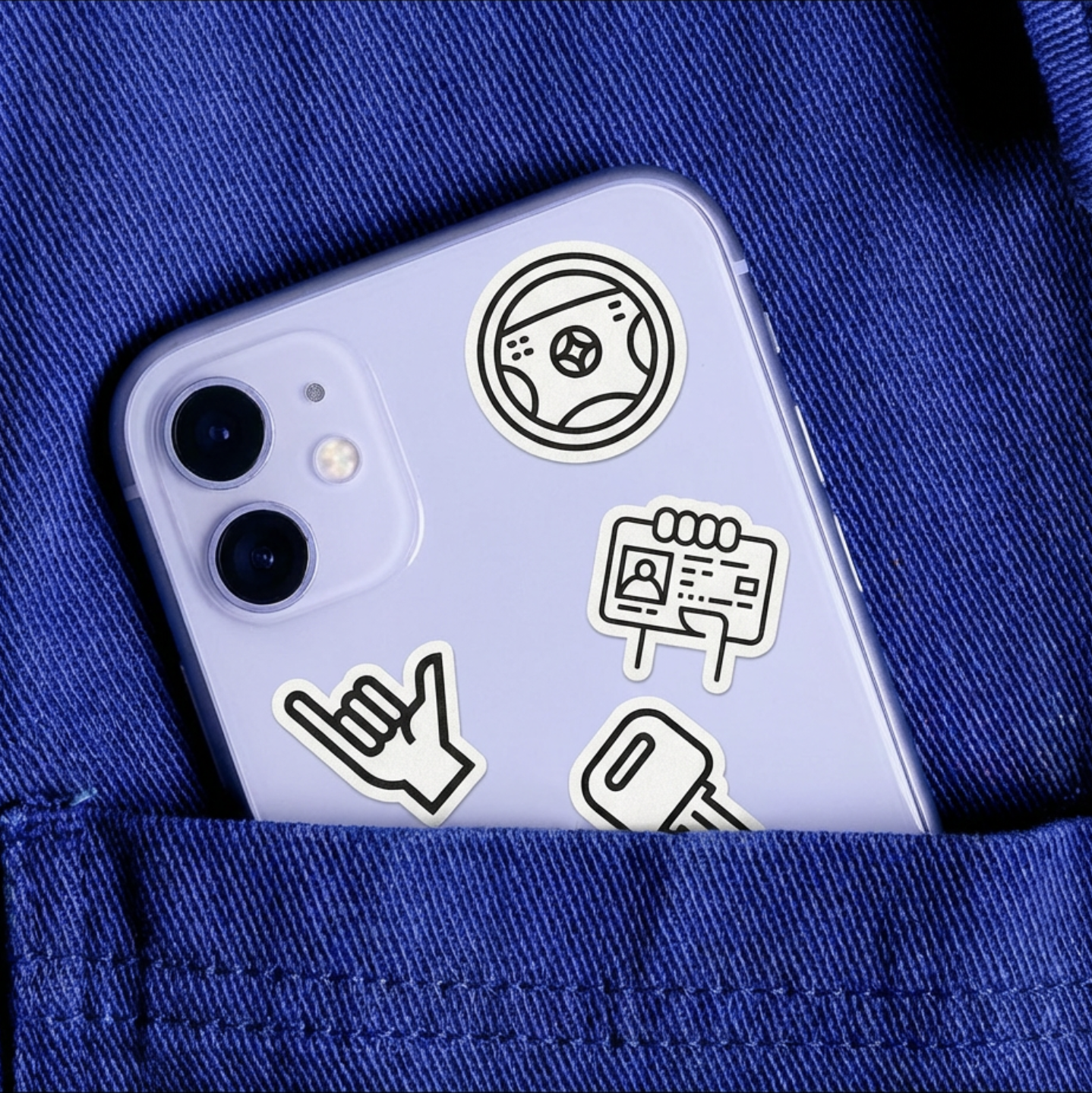 An iPhone with dance, driving, and identification stickers on the back, resting in a blue fabric pocket.