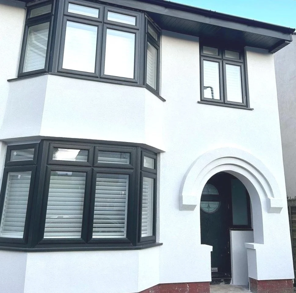 Front view of a two-story house with white exterior walls, black window frames, and a distinctive arched entryway.