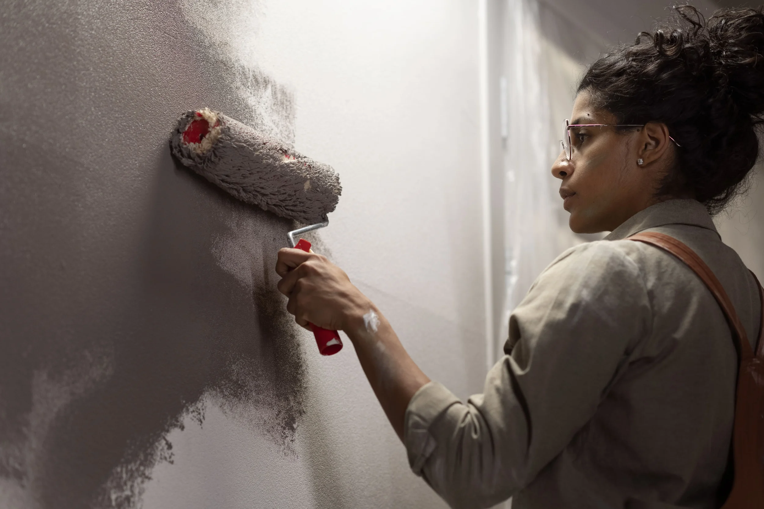 A woman painting a stucco house - Stephen Radl Painting