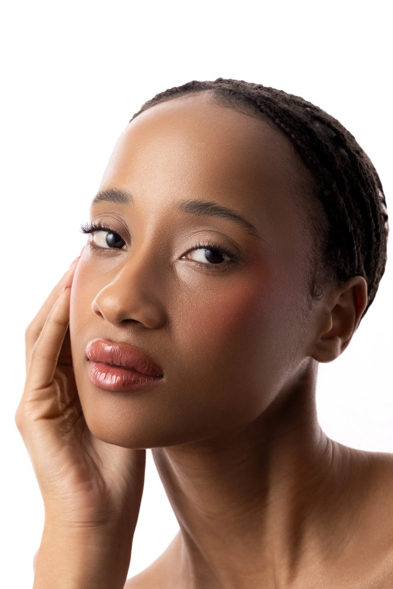 Portrait d'une femme noire avec un visage clair et des cheveux tressés, touchant son visage avec une expression neutre