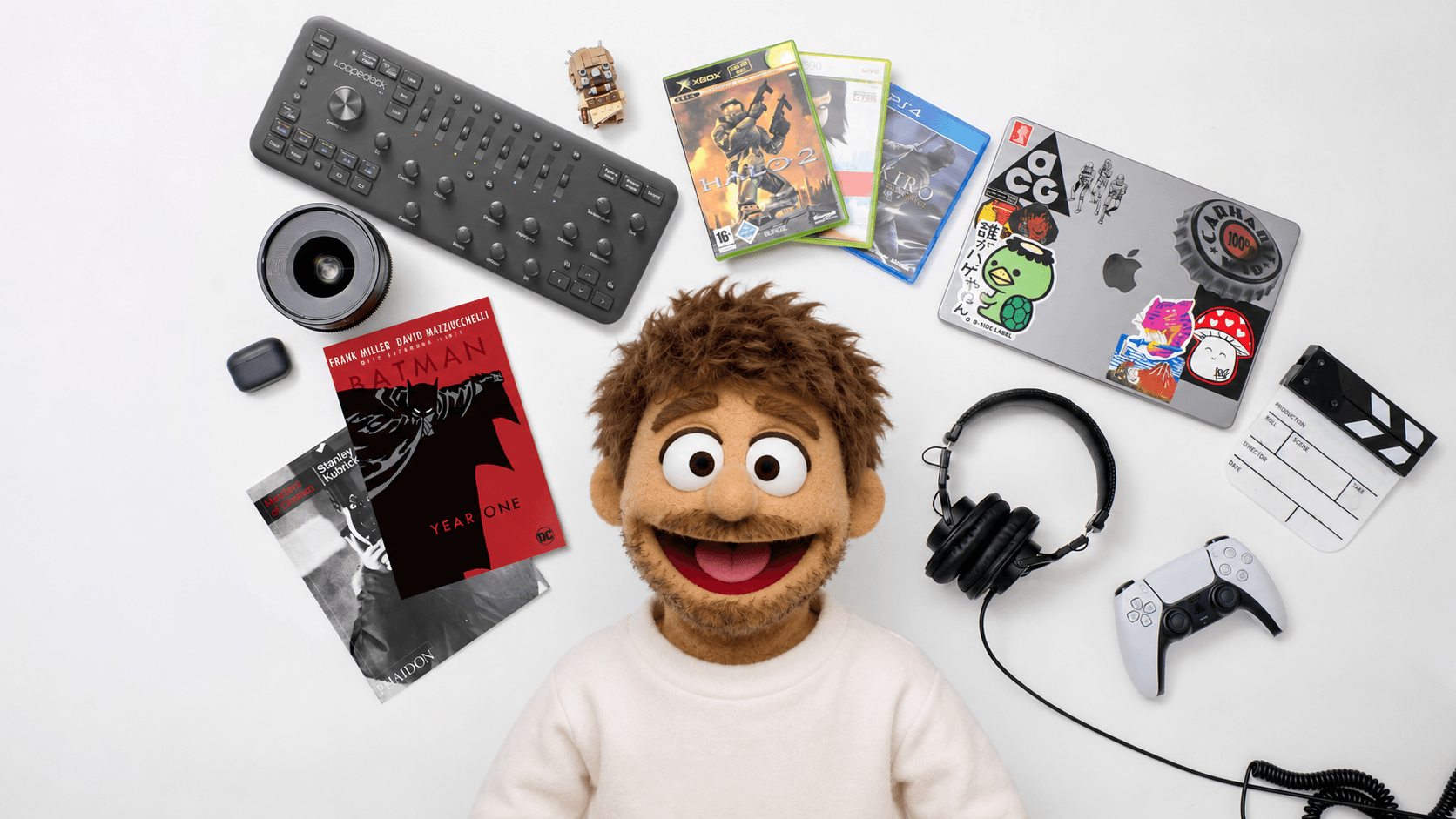 Person in a mascot costume with a large smiling face and brown hair, standing in a photography studio with professional lighting and video equipment.