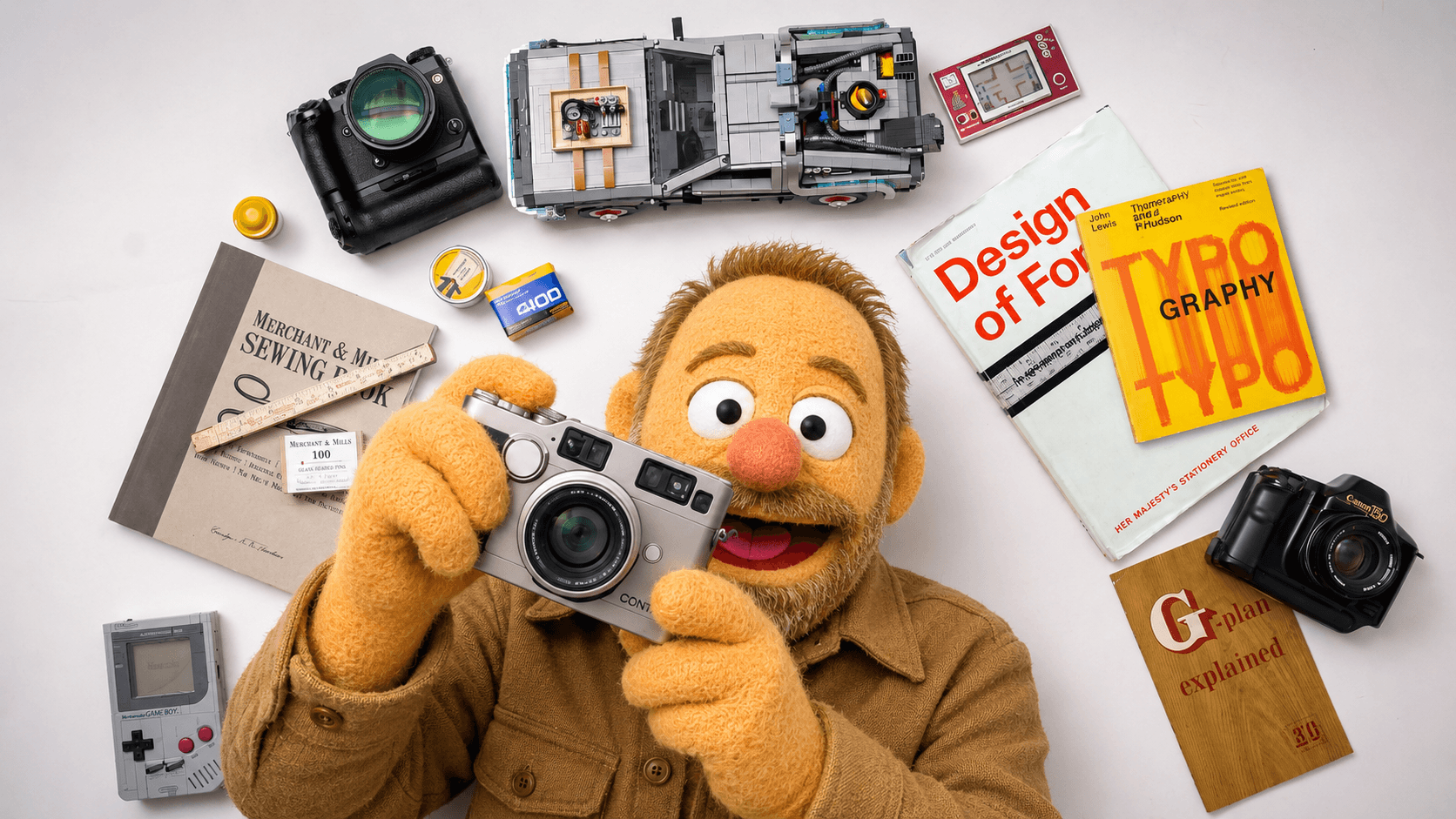 A puppet character with a yellow face, brown hair, and a serious expression, dressed in a dark blue shirt, sitting in a photography or film studio with professional lighting equipment in the background.