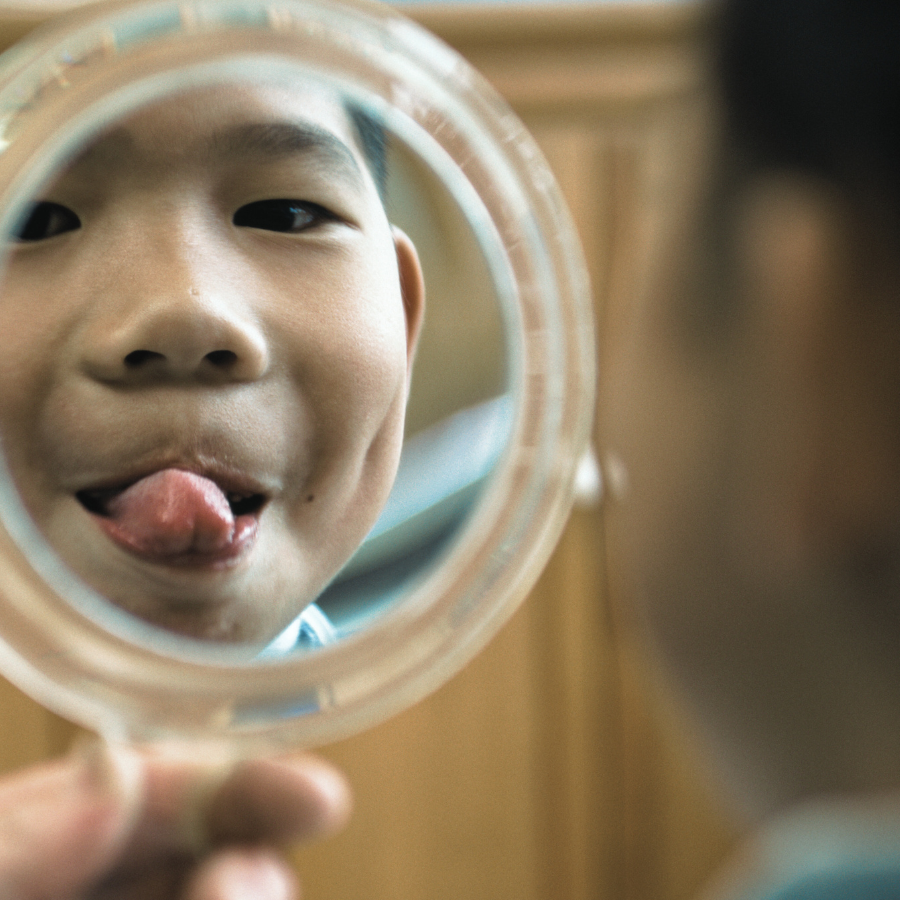 Child looking into a mirror, sticking out tongue