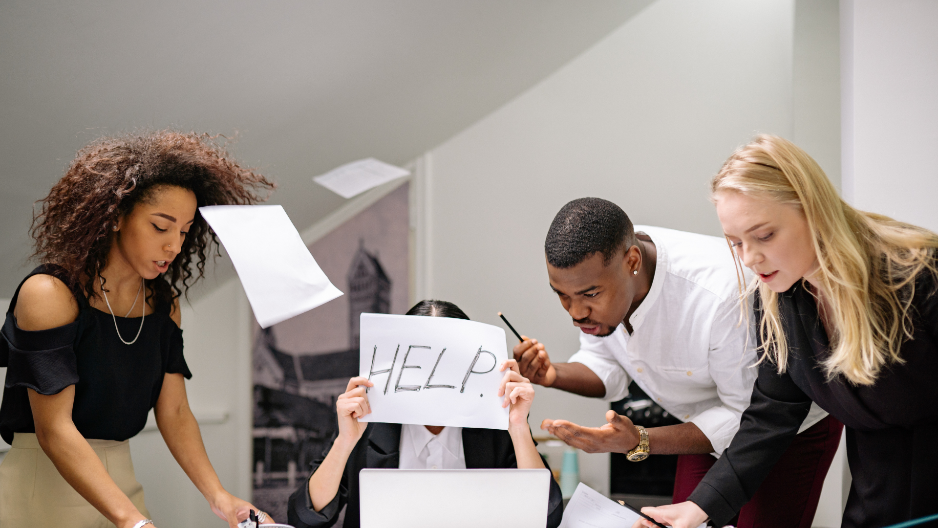 Overwhelmed worker holding “help” sign while others crowd around