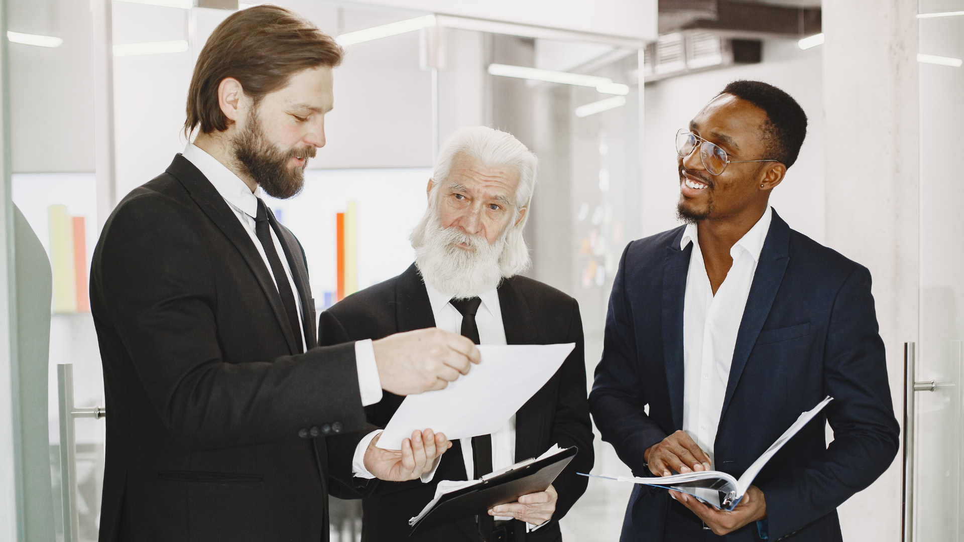 3 men in a meeting reading documents