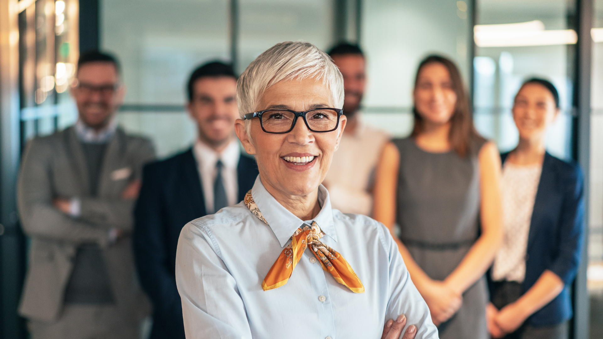 Senior leader standing confidently in front of a diverse professional team