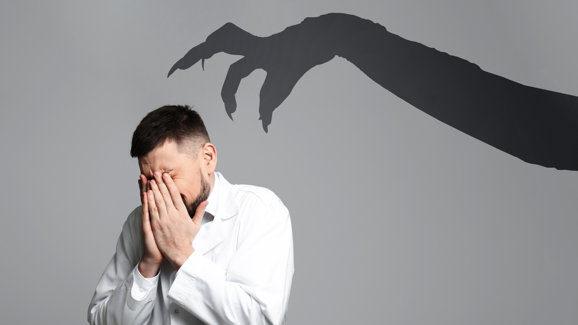 Man covering face with shadow hand above him