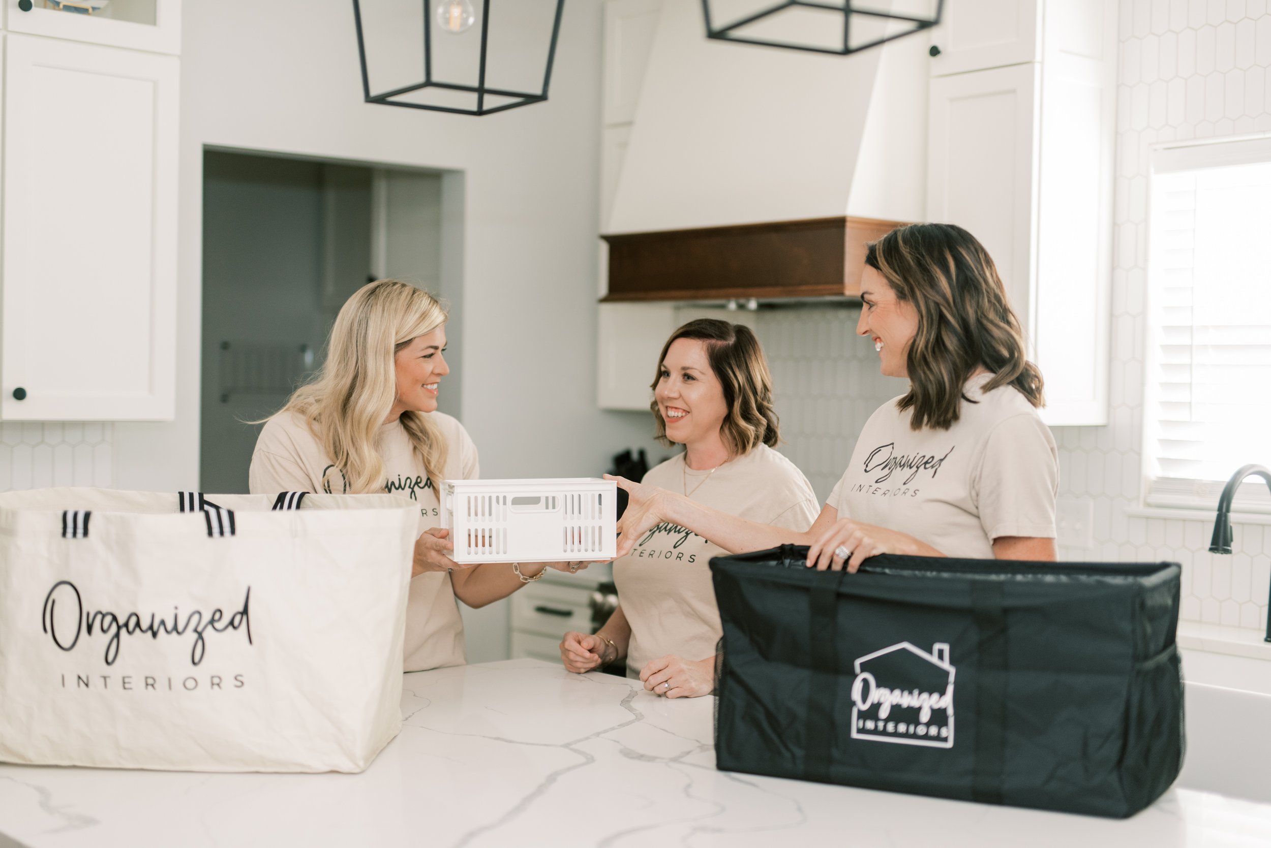 Professional organizers from Organized Interiors in St. Louis preparing storage bins during a home organization project in a modern kitchen.