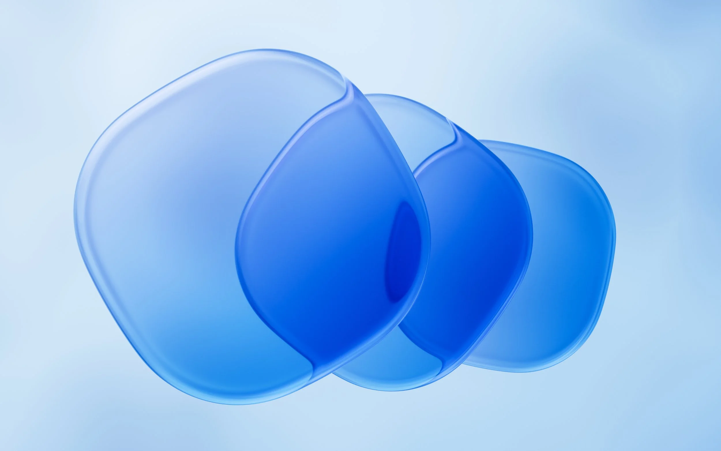 Close-up of three overlapping translucent blue contact lenses on a light blue background.