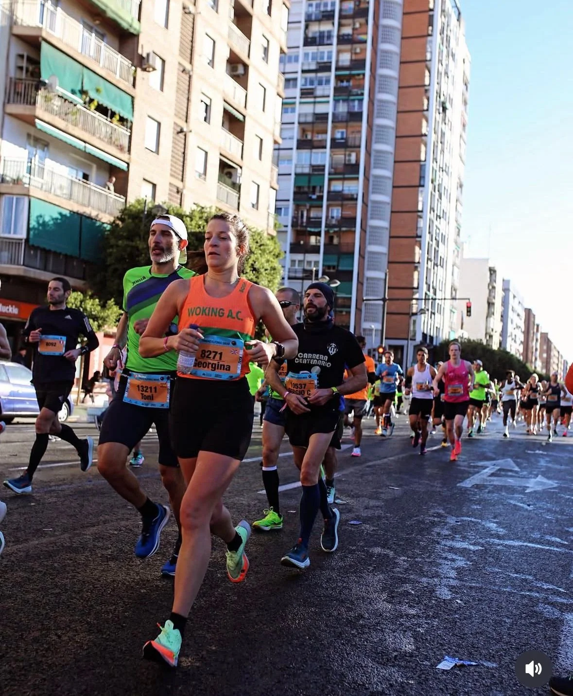 Group of runners participating in a street marathon amidst urban buildings.