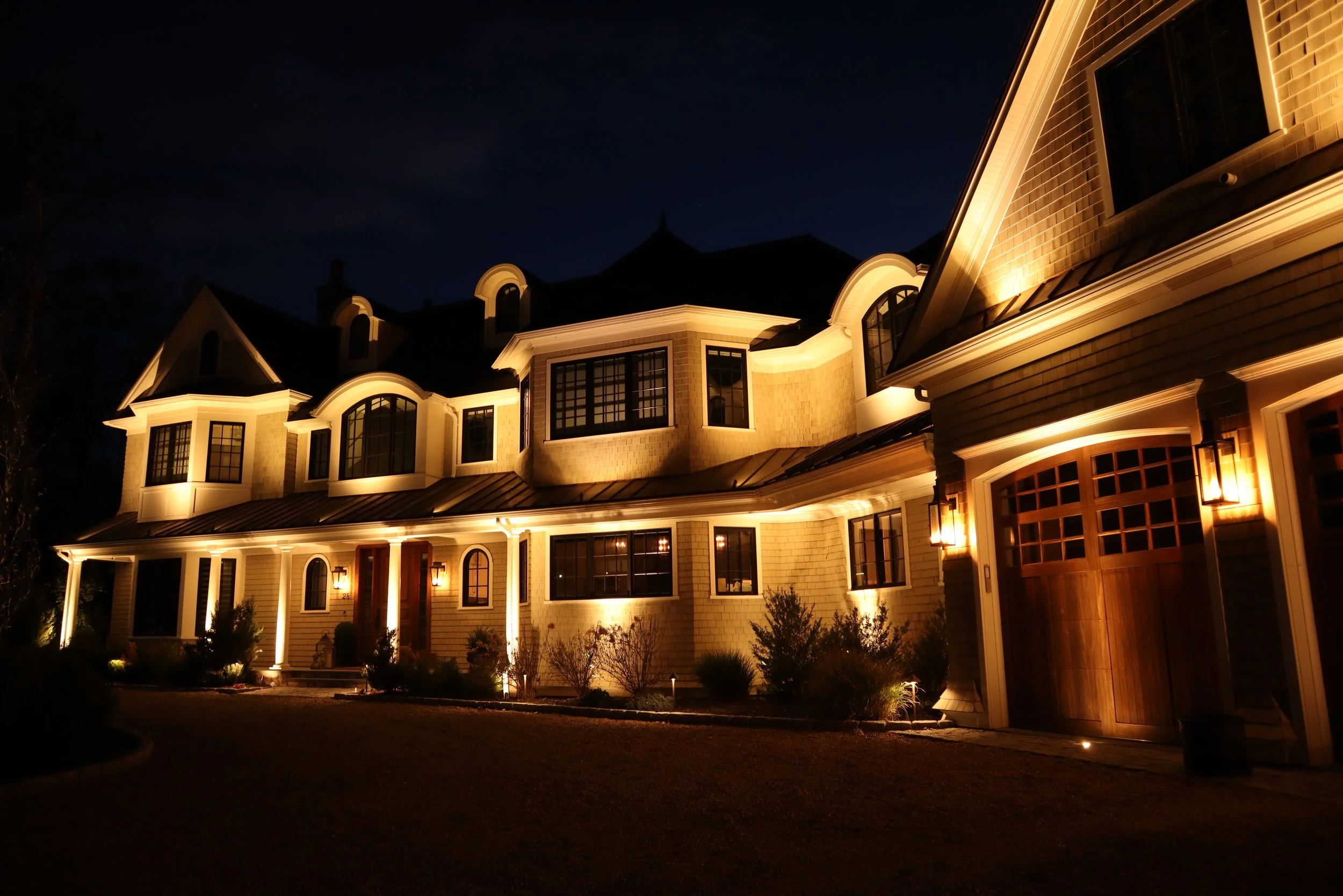 Architectural facade lighting accenting rooflines, dormers, and entry features on a custom home in Middleton, Massachusetts