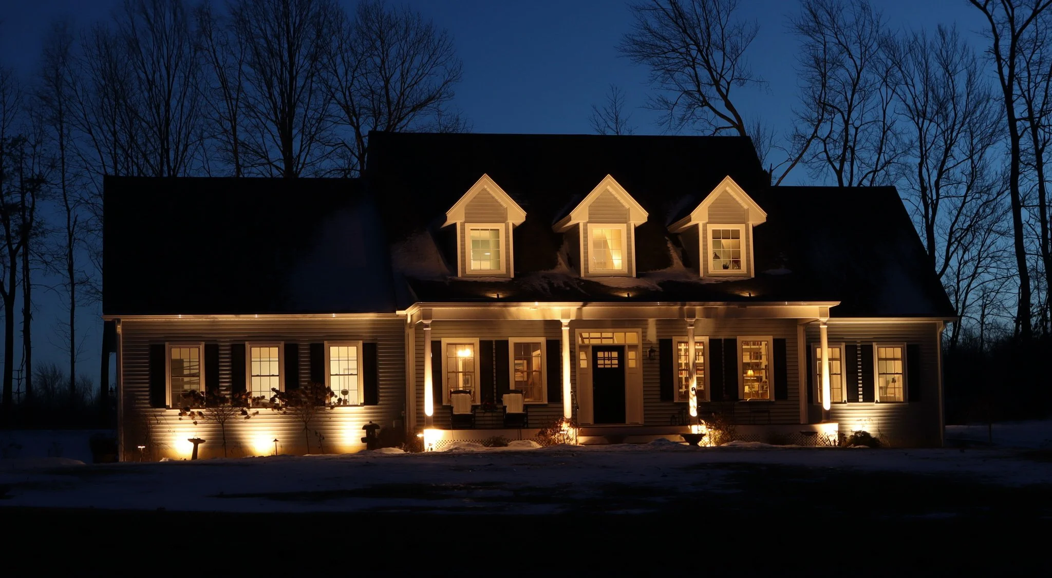 House with dormer windows and exterior lights at night