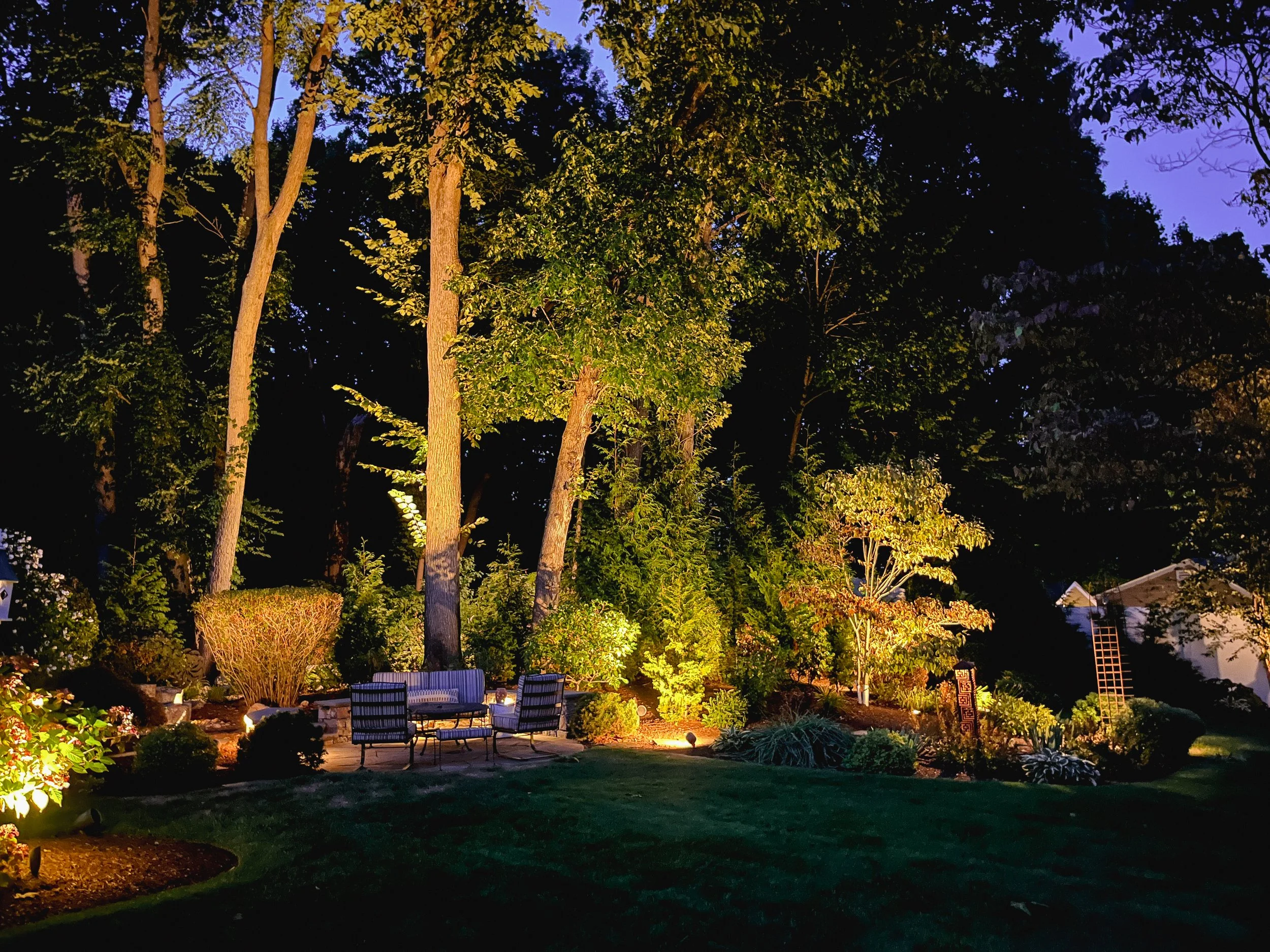 Custom landscape and garden lighting illuminating mature trees and outdoor living spaces in Arlington, Massachusetts