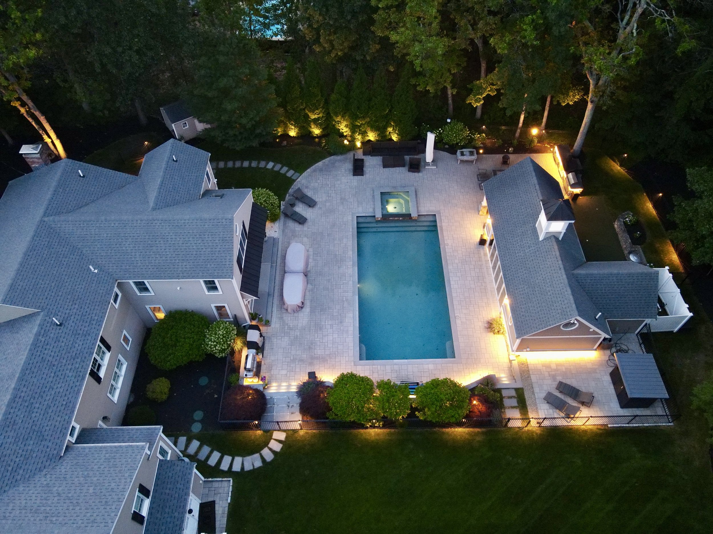 Custom pool and patio lighting with illuminated retaining walls and outdoor entertaining spaces in Middleton, MA.