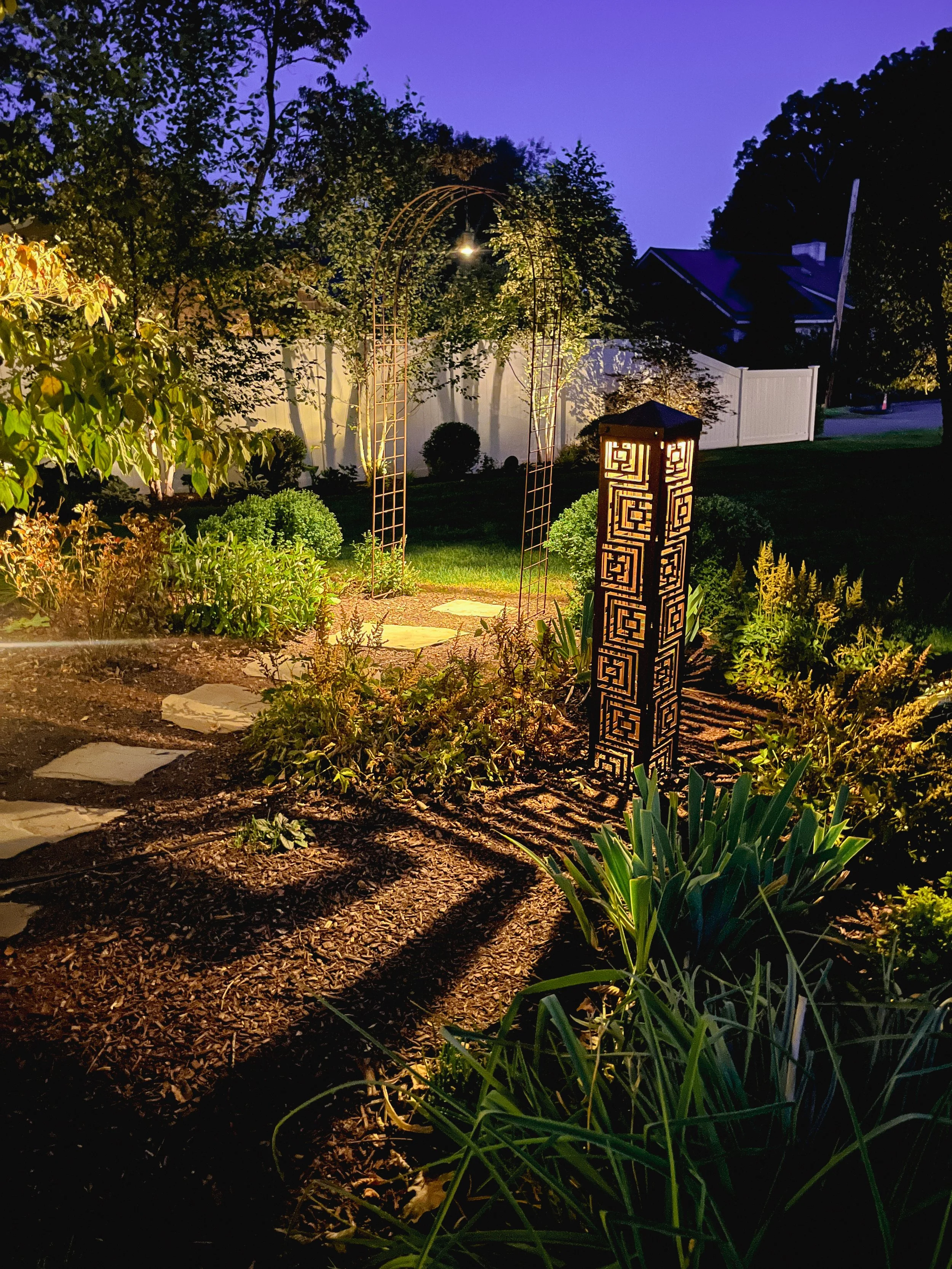 Landscape lighting highlighting a decorative garden arbor and pathway in Arlington, MA