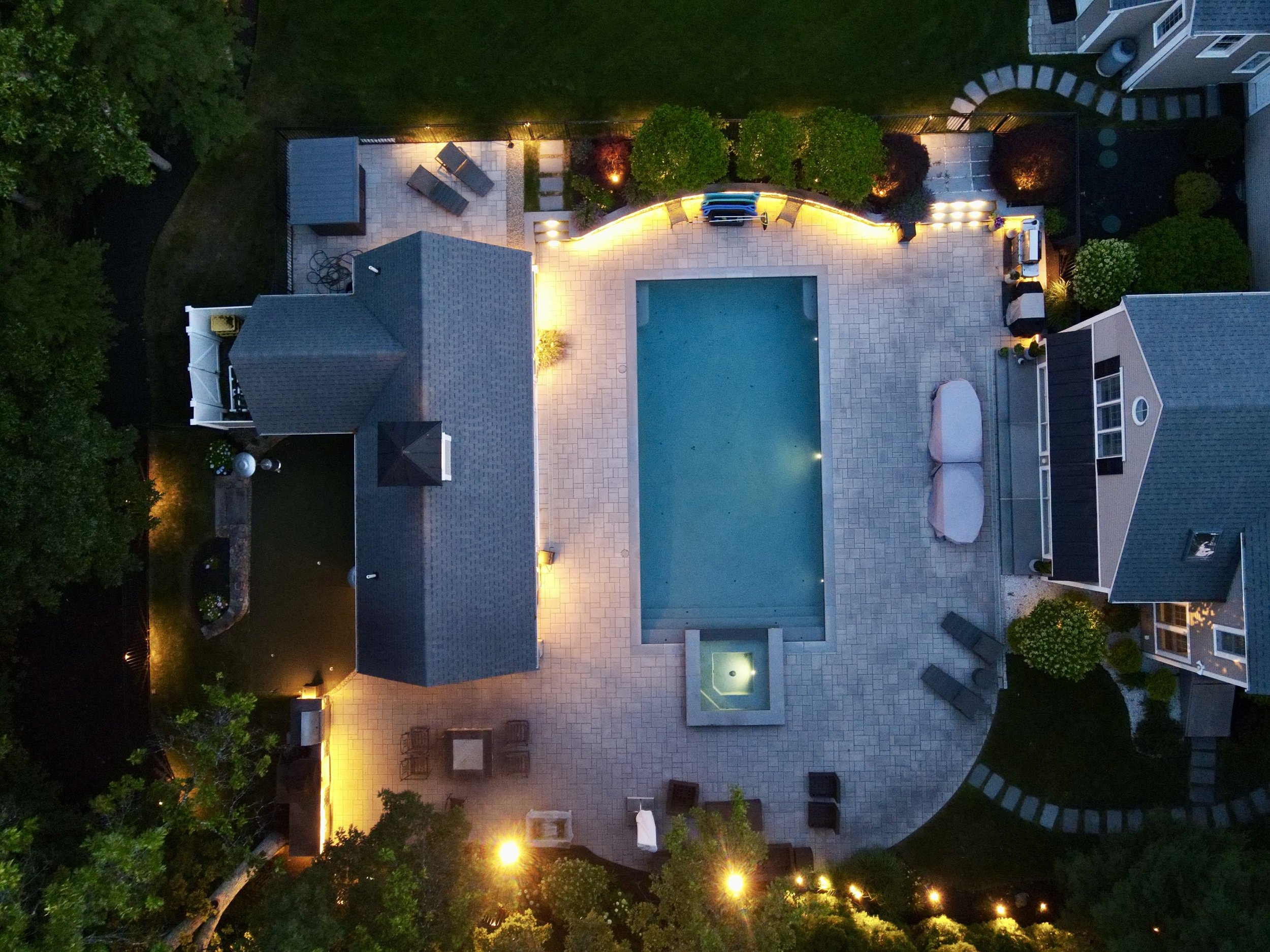 Luxury backyard lighting featuring a pool, outdoor pavilion, landscape lighting, and architectural lighting in Middleton, Massachusetts.