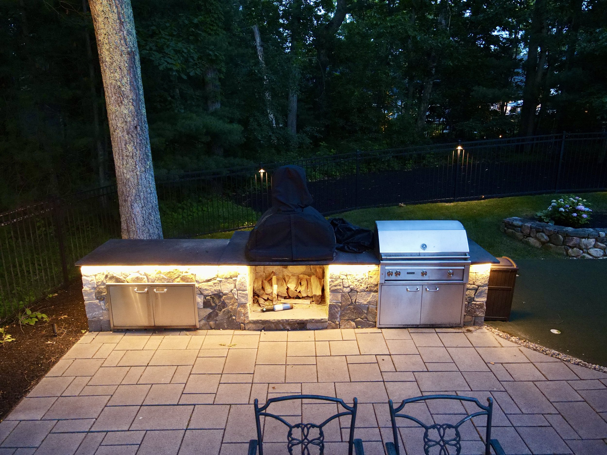 Outdoor kitchen illuminated with integrated linear lighting in Middleton, Massachusetts.
