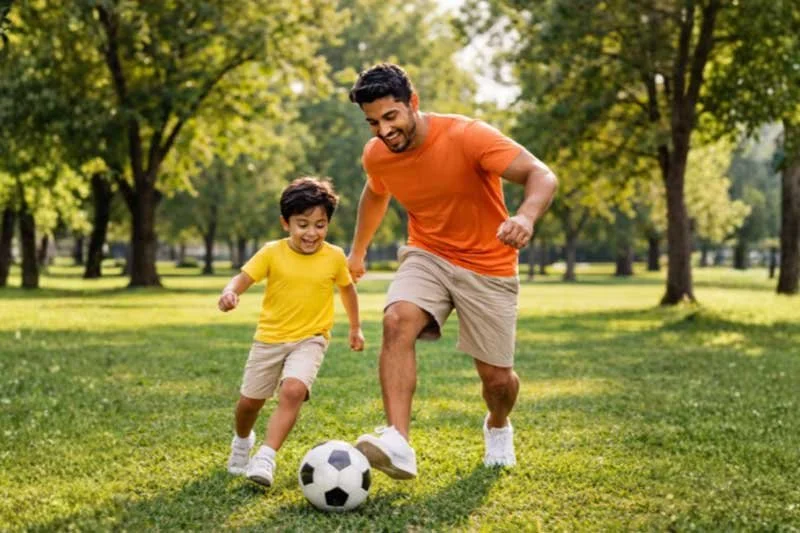 Father and son kicking a soccer ball on a field, supporting children's emotions