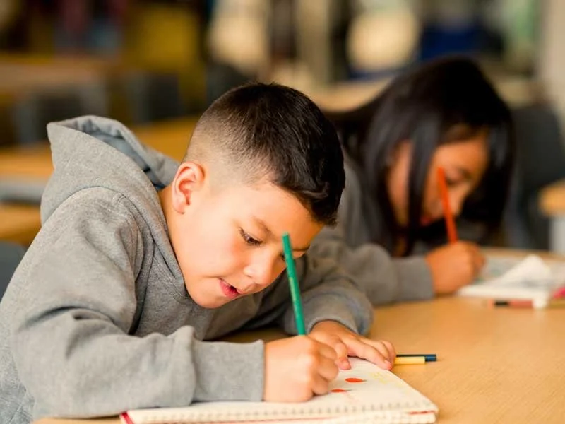 Children holding pencils and working on schoolwork, ending the school year strong