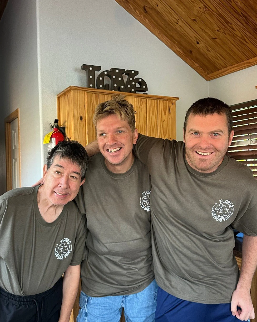 3 men in matching camp shirts at a cabin