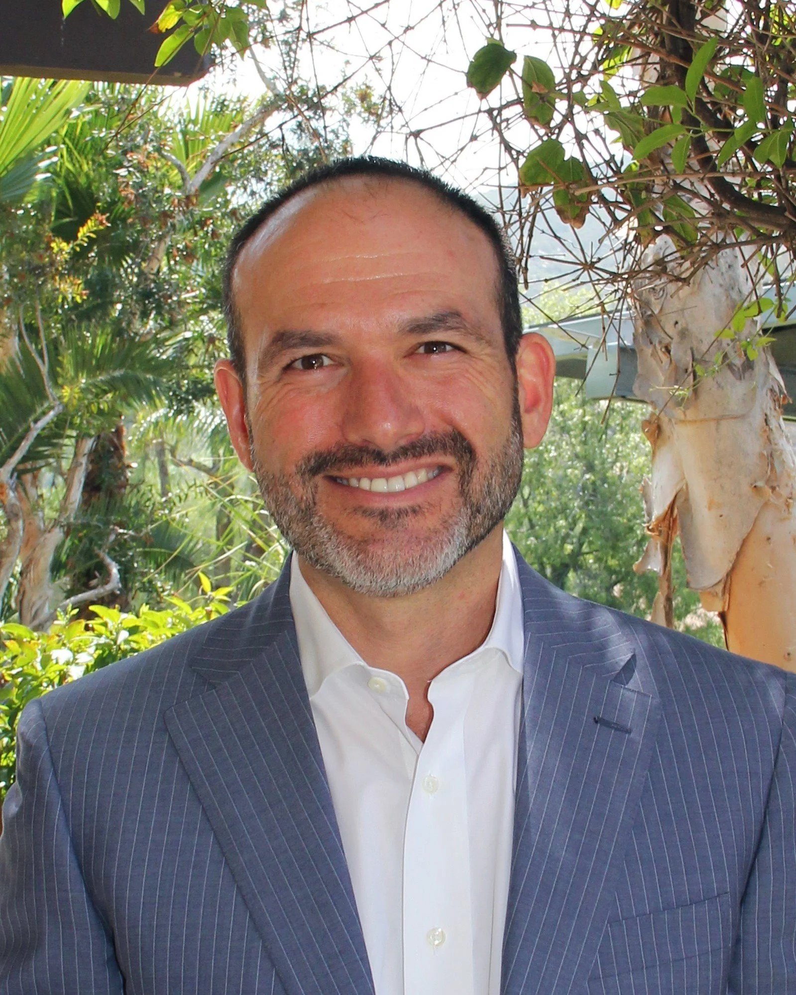 Man in a blue suit jacket in front of greenery