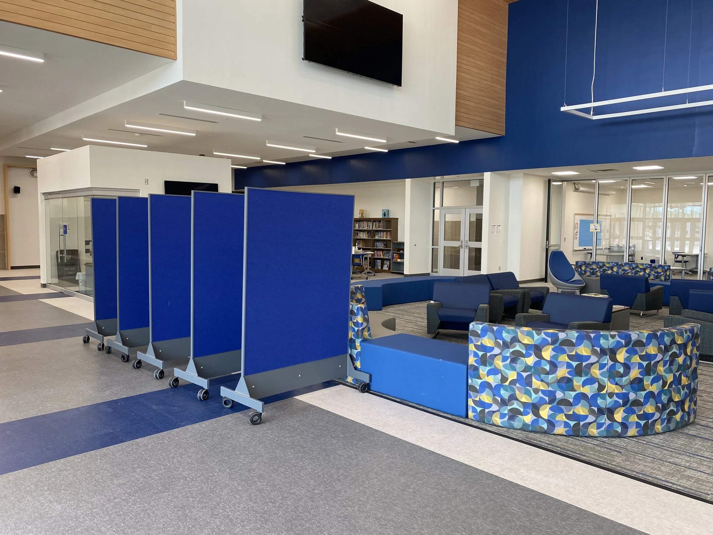 Multiple TAG Mobile bulletproof whiteboards showing acoustic panel side in a modern school commons area