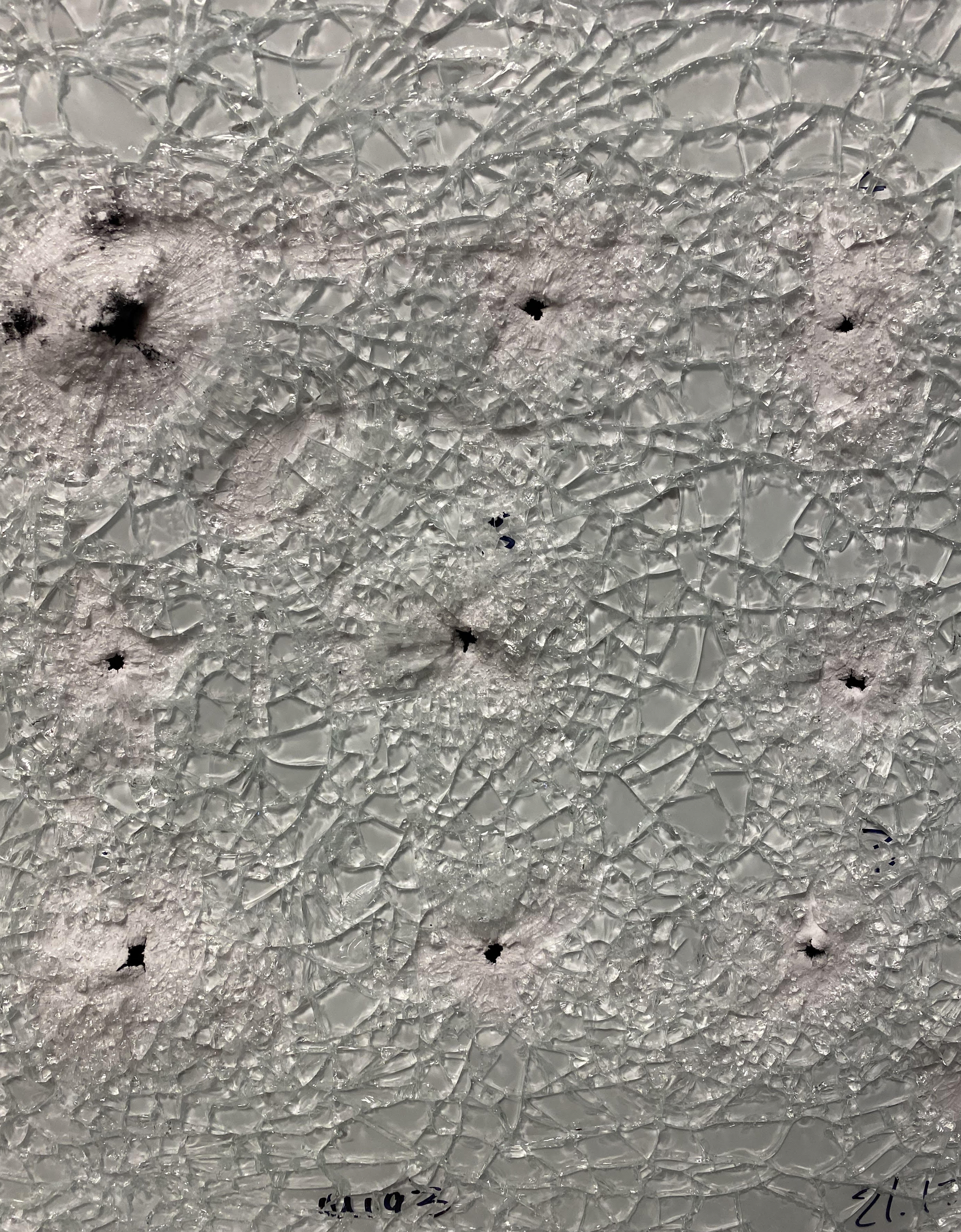 Ballistic glass test panel showing bullet impacts after ballistic resistance testing for protective window and vestibule applications.