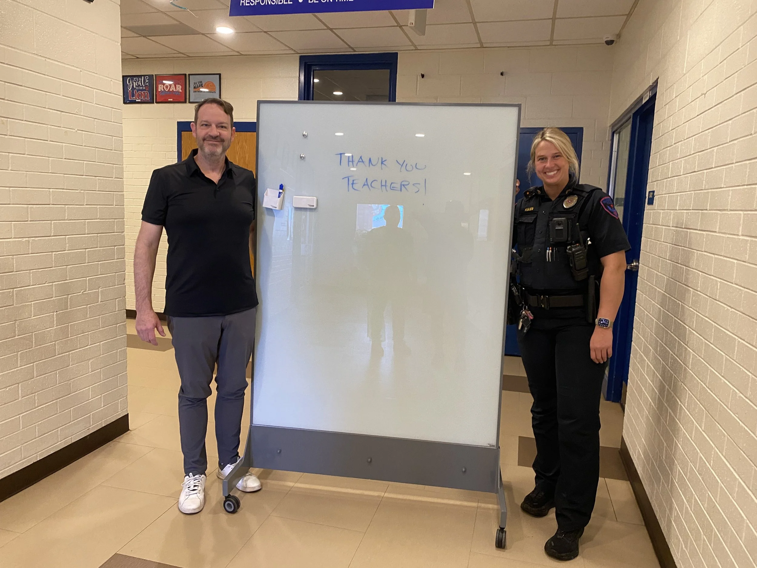 Scott Newman with school resource officer demonstrating TAG Mobile bulletproof whiteboard for school safety