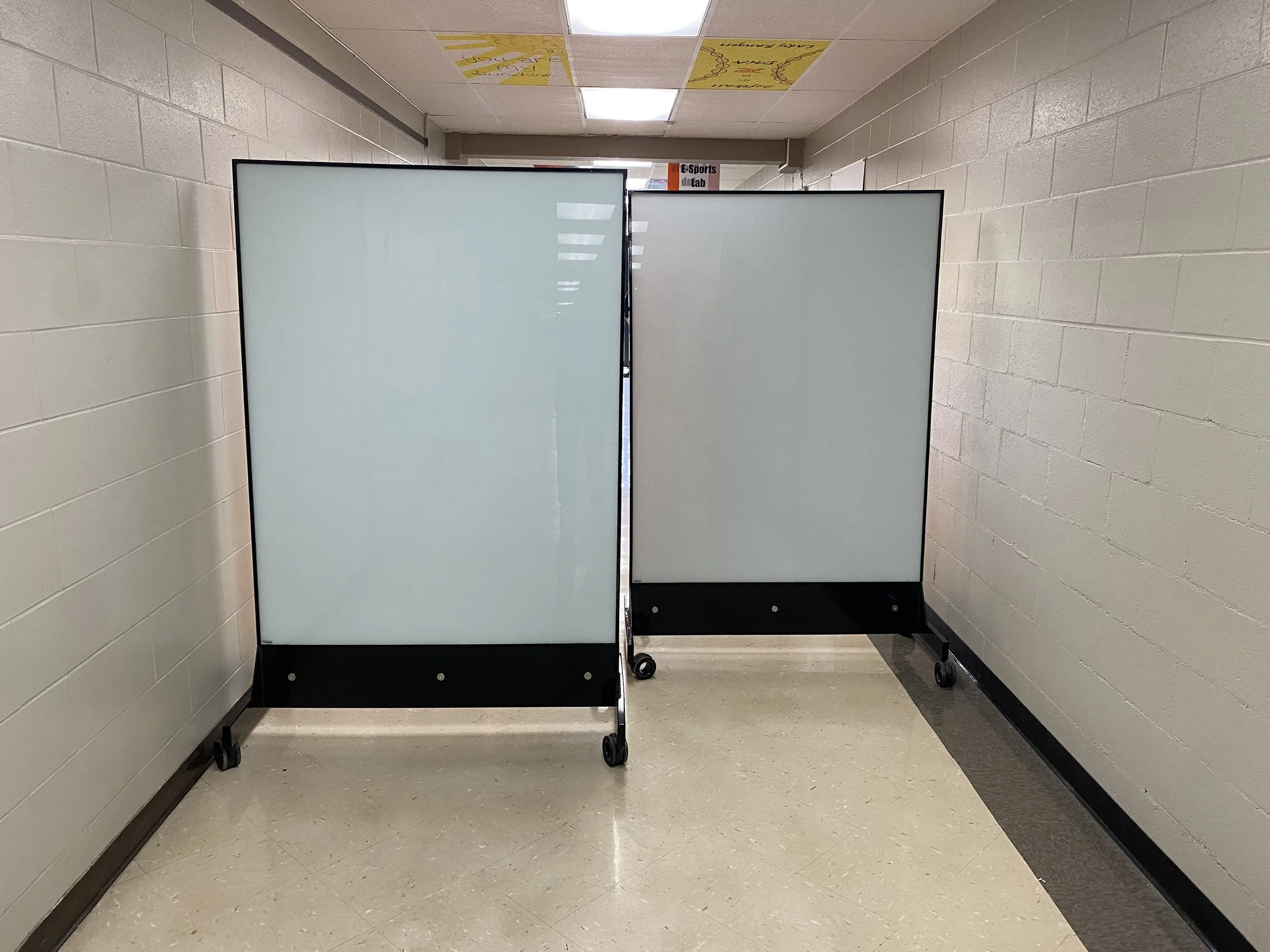Two TAG Mobile™ bulletproof mobile whiteboards positioned across a school hallway to create a physical barrier and redirect pedestrian traffic.