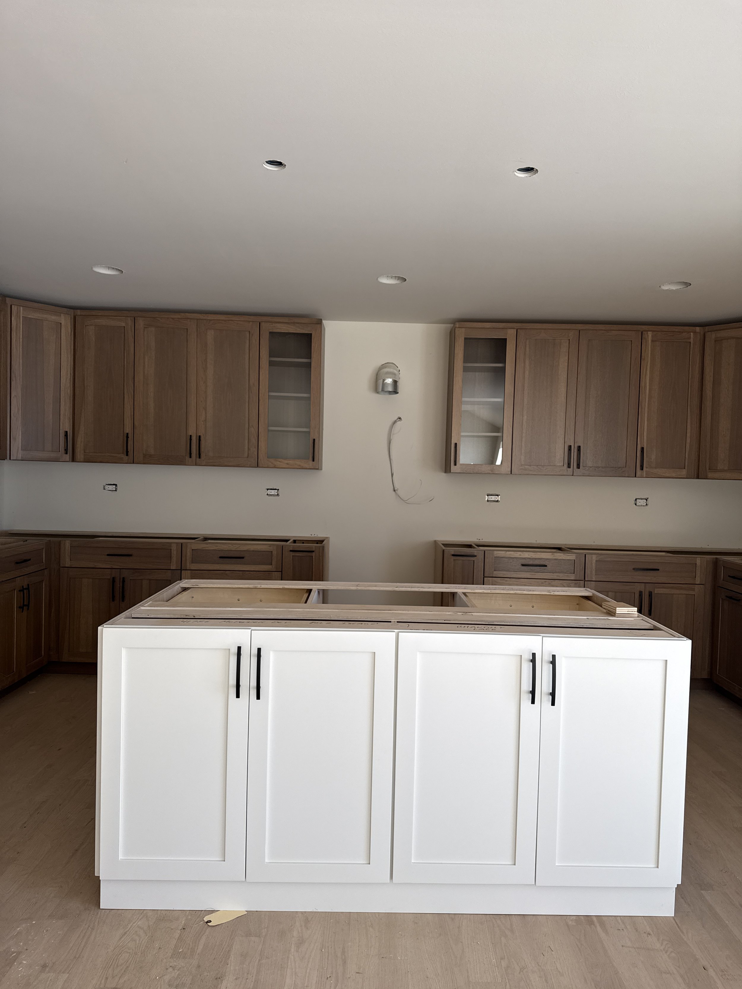 unfinished kitchen with white island and wood cabinets
