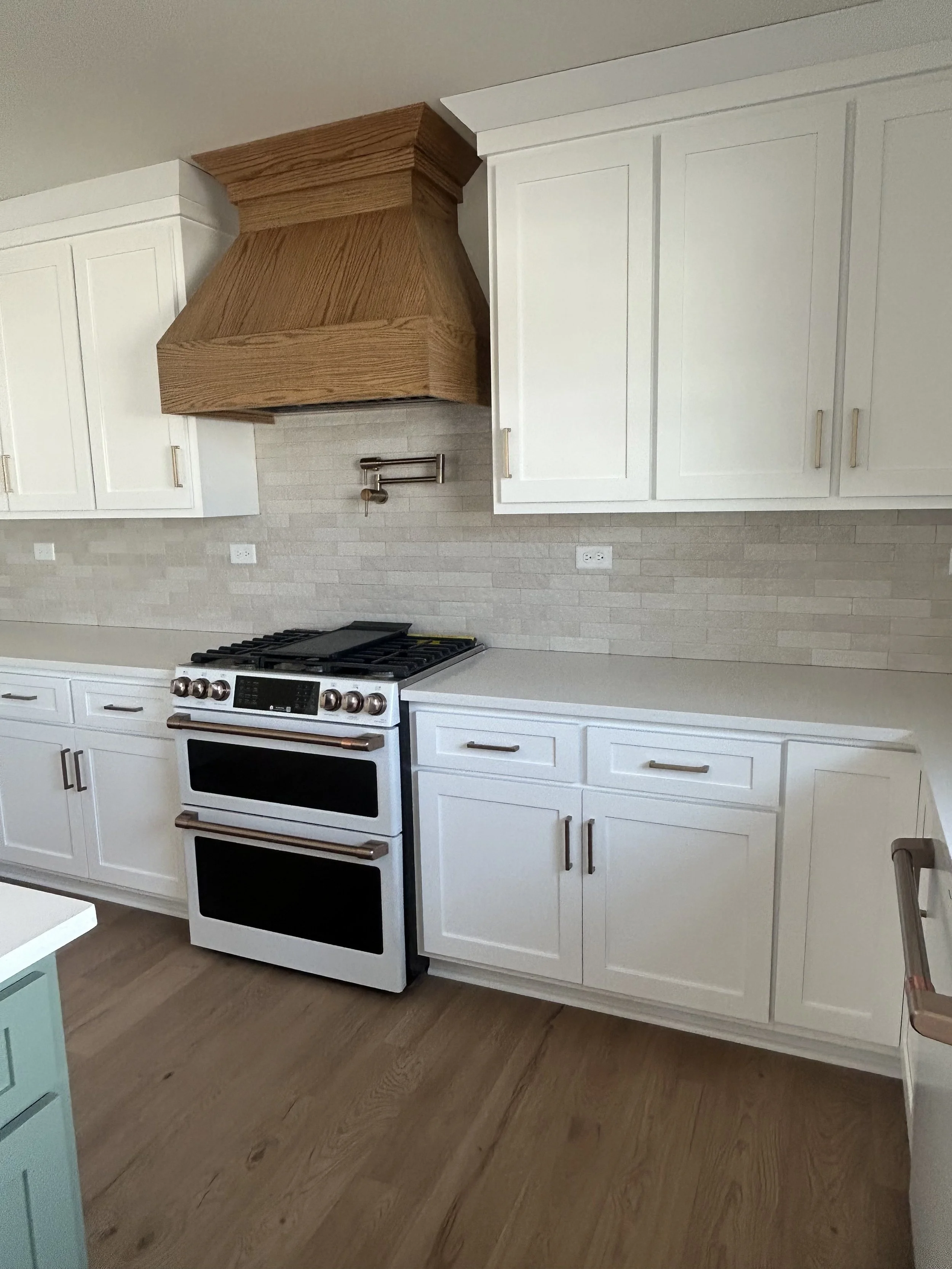 Kitchen with white cabinets, a white stove, a beige tile backsplash, and a wooden range hood.