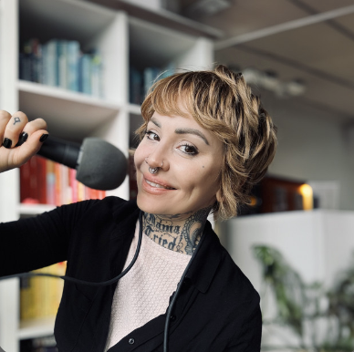 Photo of podcast host, Elle Stanger, smiling while holding a microphone