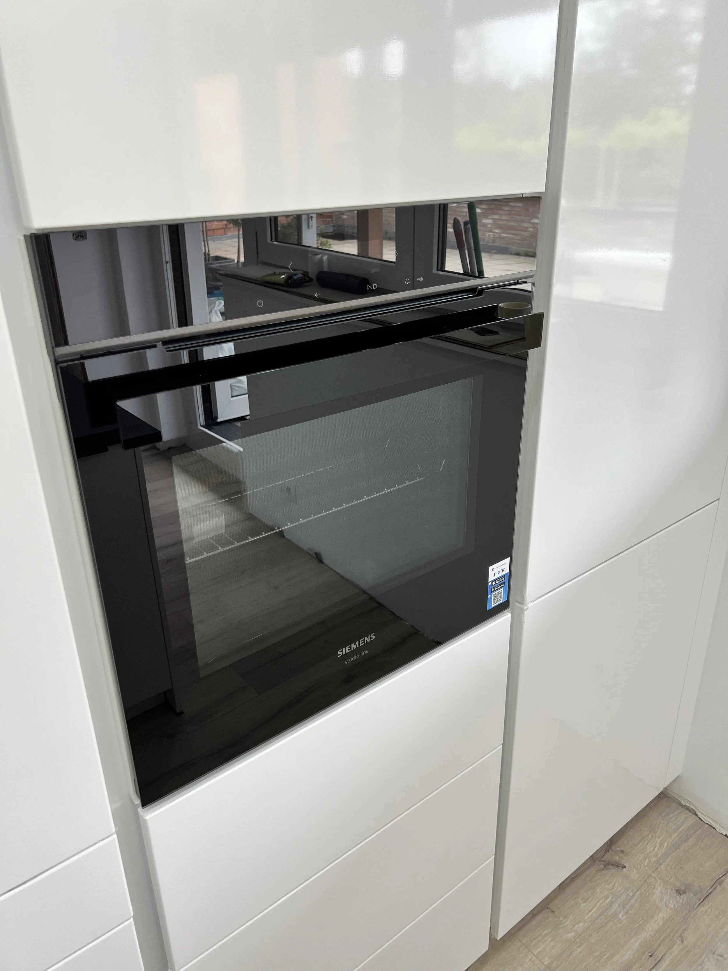 Built-in Siemens oven with a black glass door, integrated into white cabinetry.