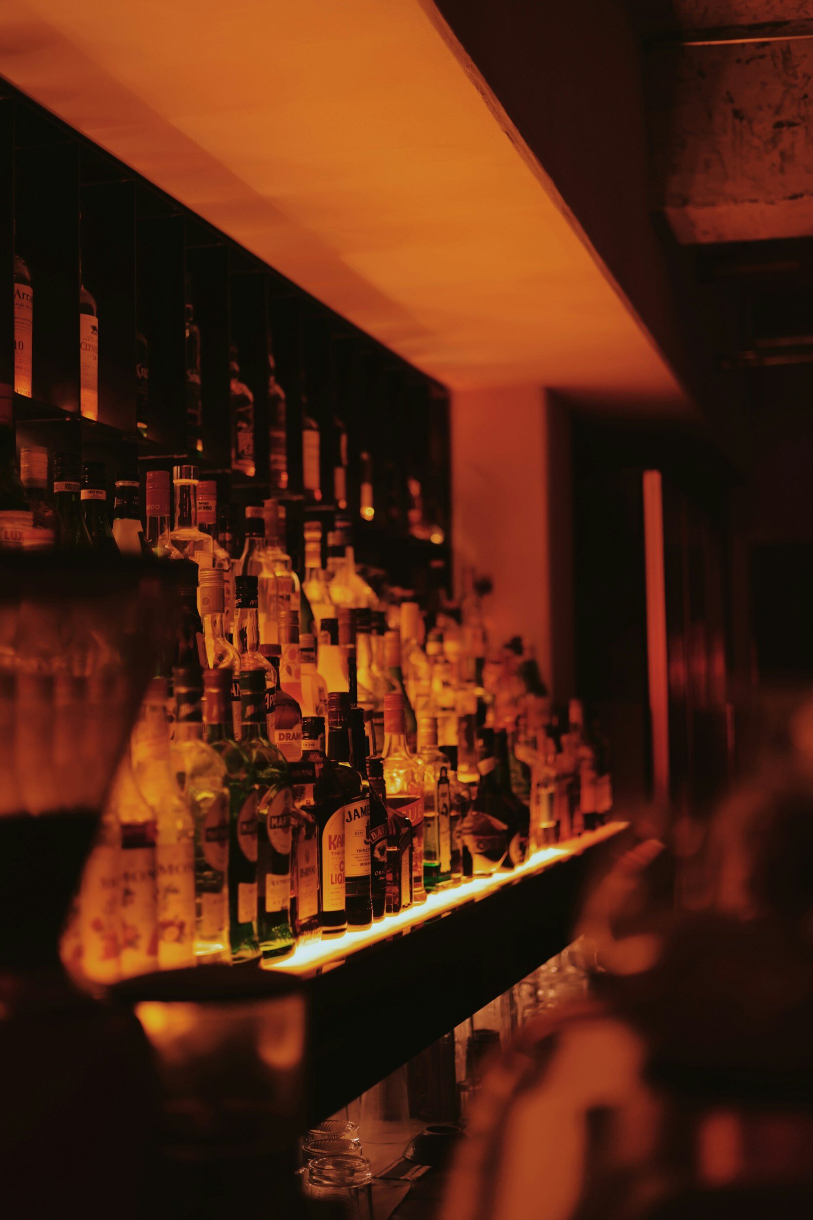 Dimly lit bar with various liquor bottles on shelves