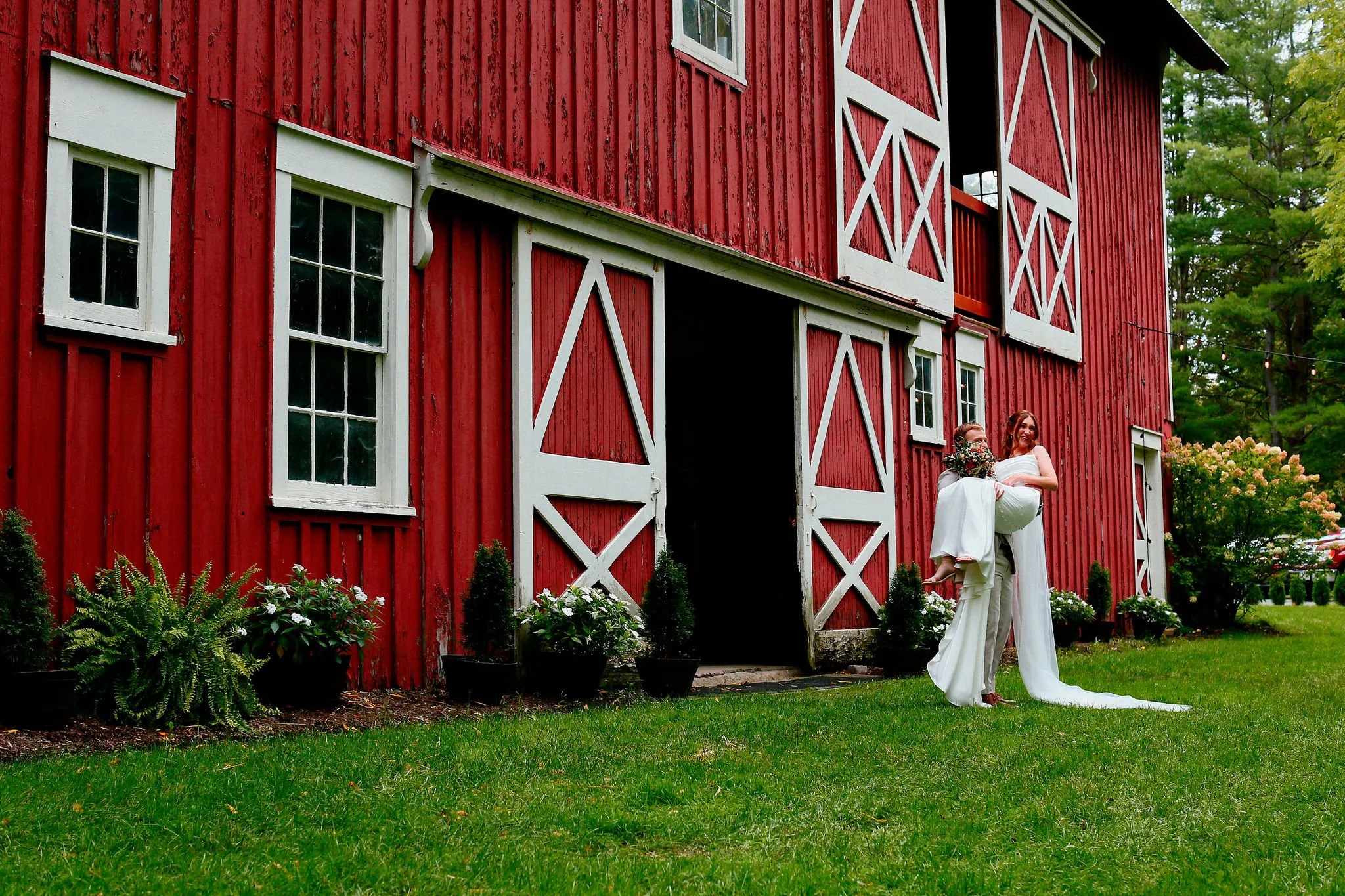 Bride in white lace dress holding bouquet in doorway